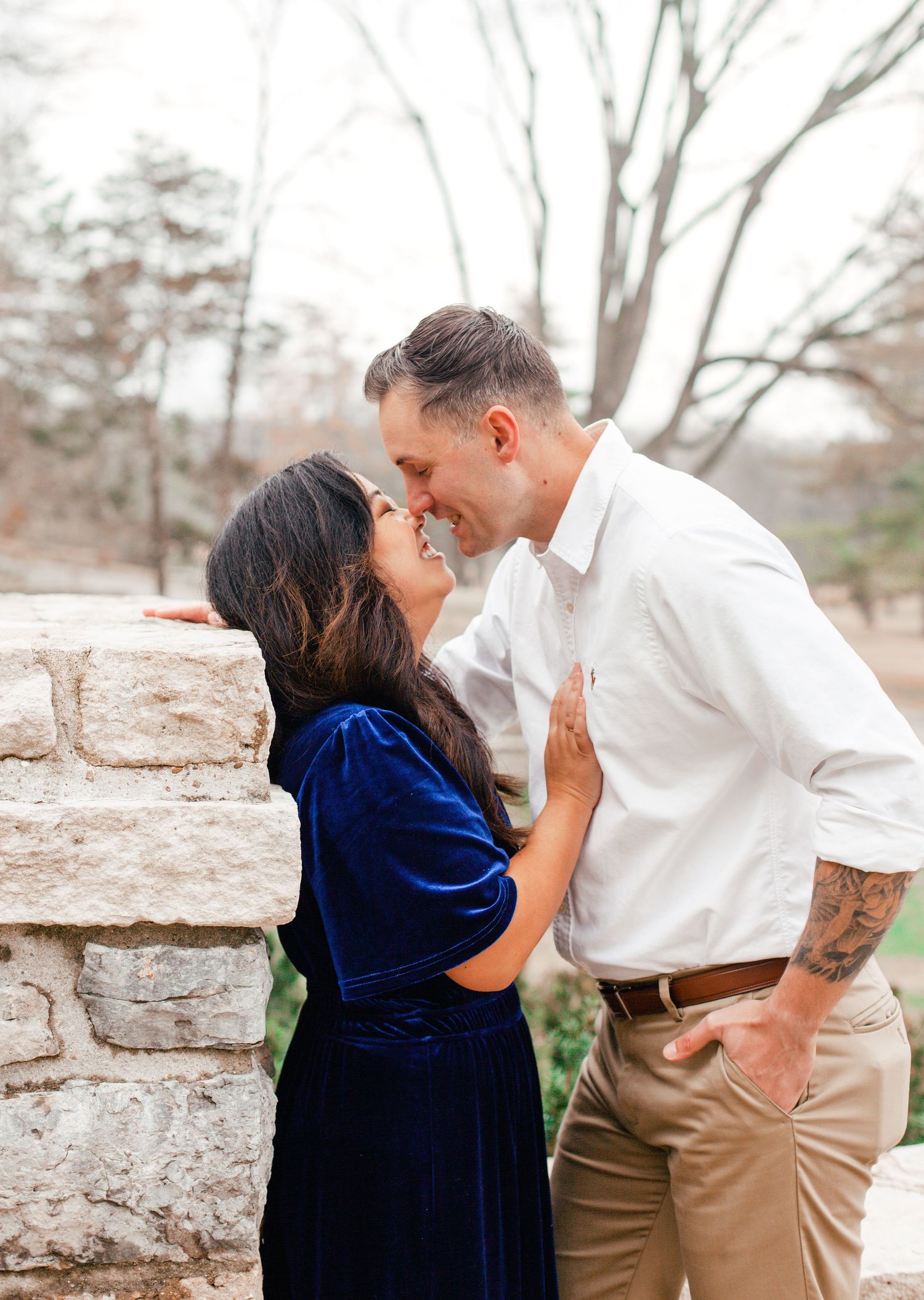 A romantic couple shares tender moments in a series of photos against a stone wall, with one wearing blue velvet.