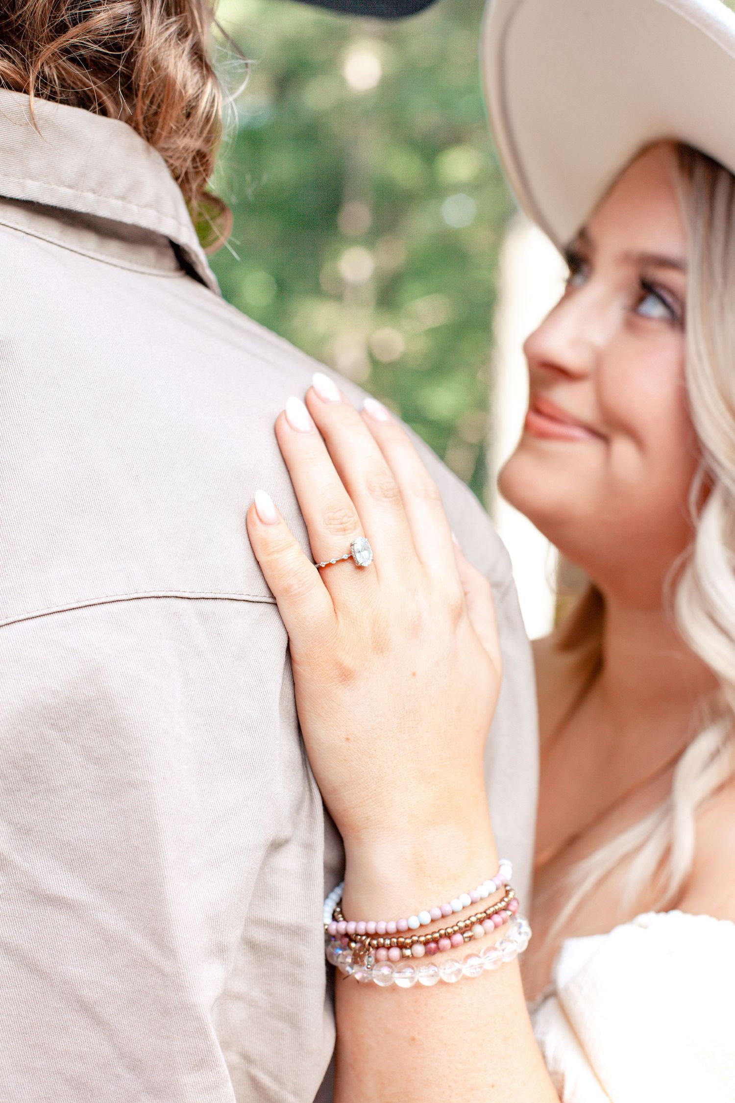 A close-up engagement photo showing a diamond ring and stacked bracelets.