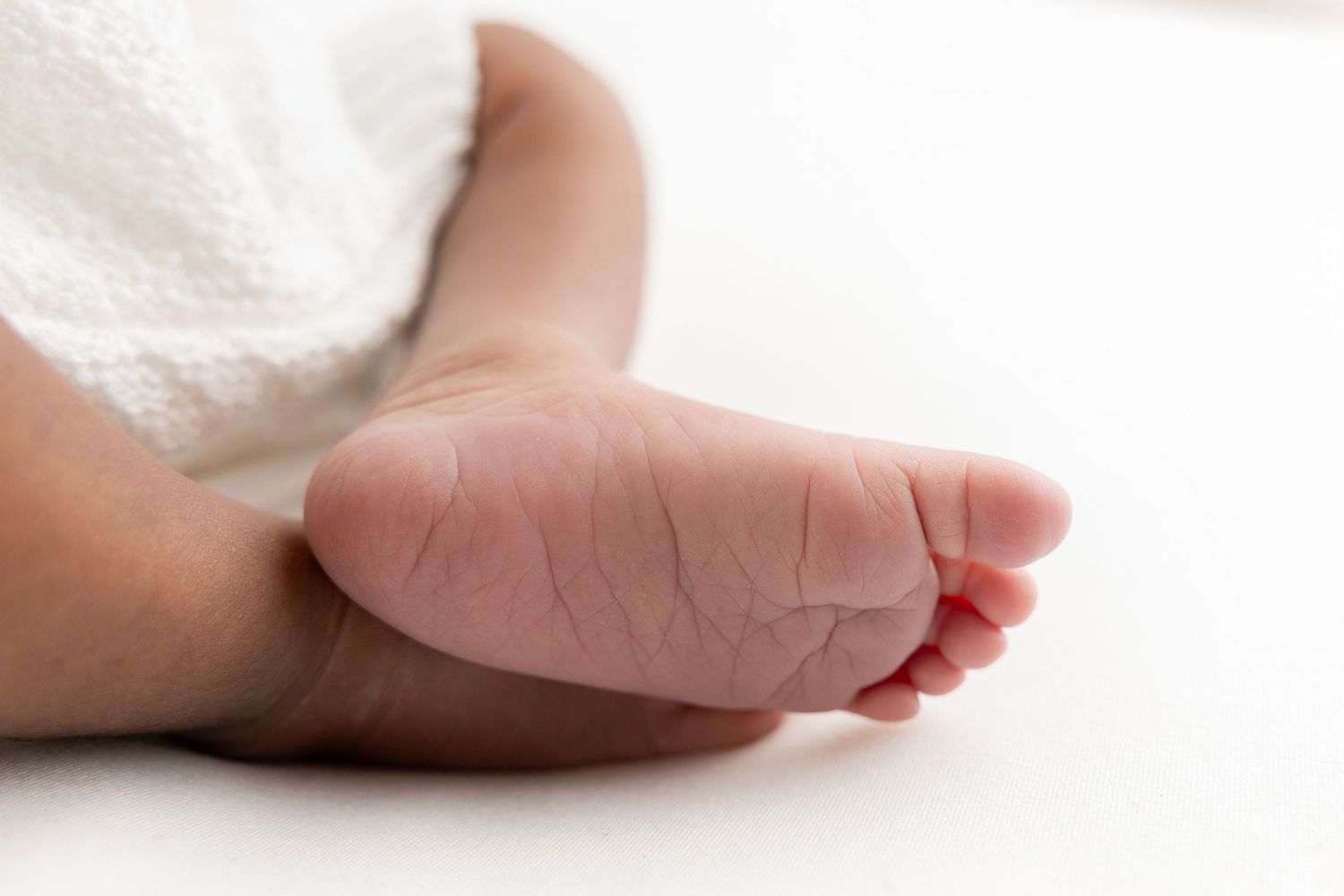 Close-up of tiny baby feet against white background.