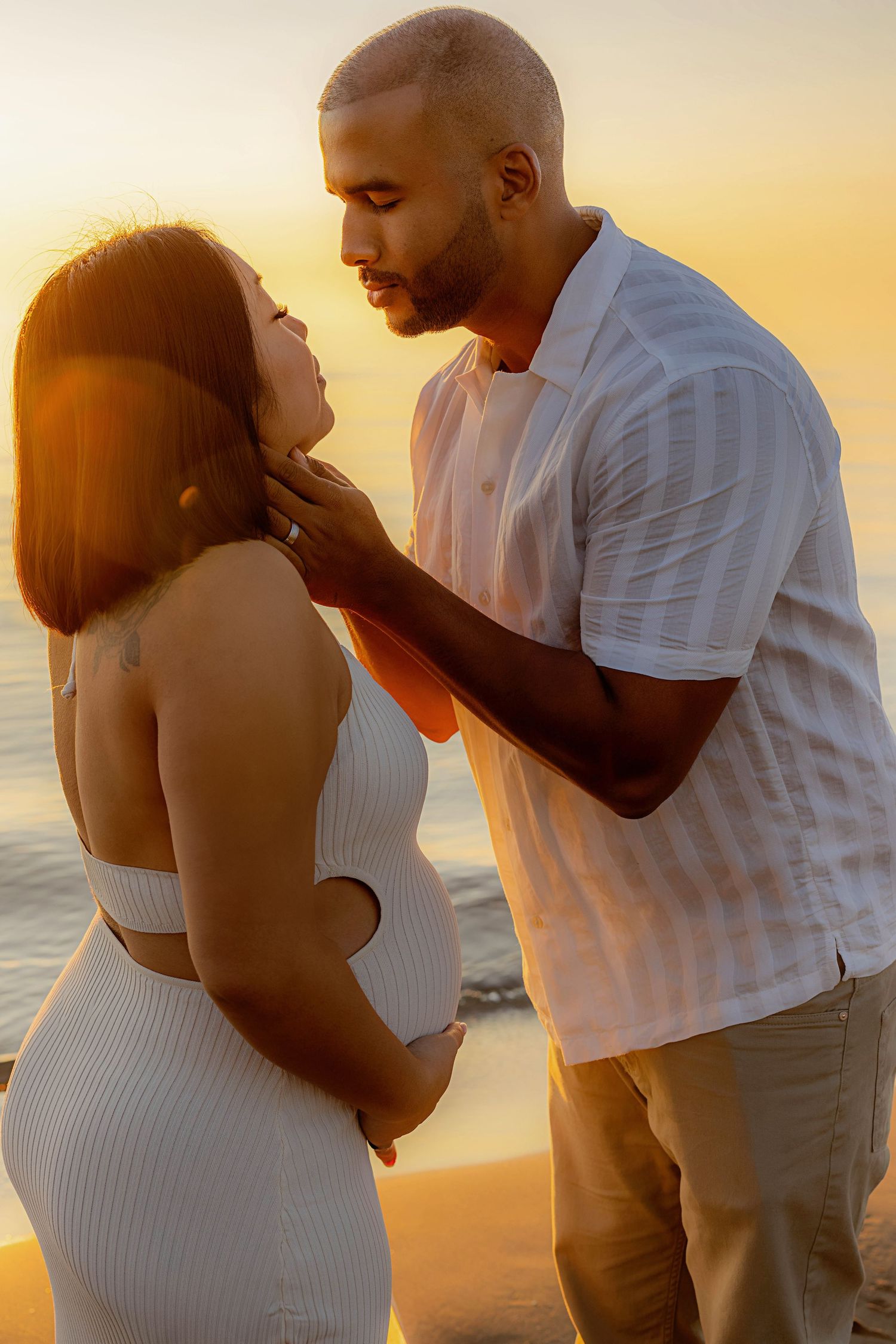 Romantic sunset beach photoshoot with couple in white outfits.