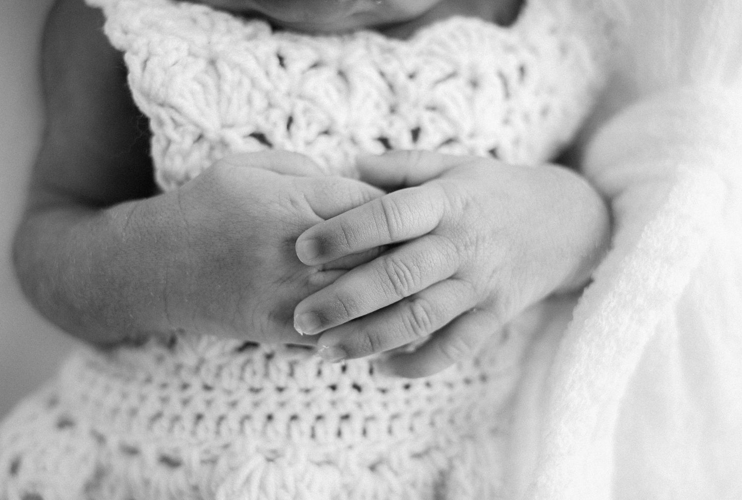 Artistic black and white detail of baby wearing crochet dress.
