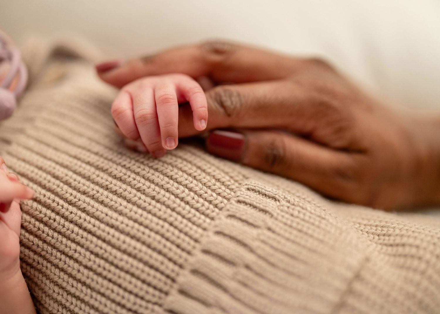 Close-up of hands gently touching a soft beige knitted fabric texture.