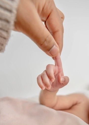 Close-up of gentle hand touching tiny baby toes in soft lighting.