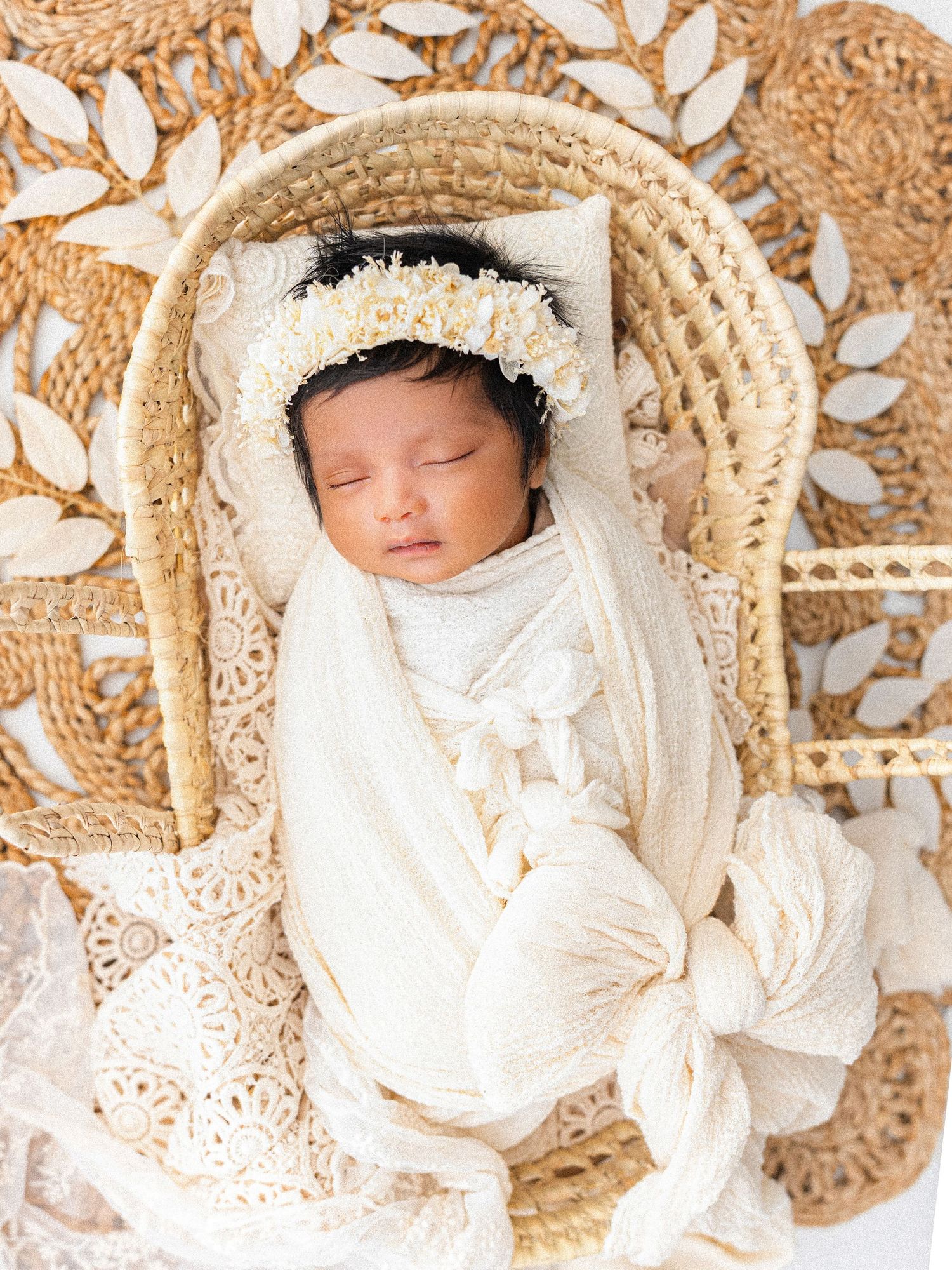 Newborn dressed in white lace outfit sleeping on vintage lace backdrop in sepia tones.