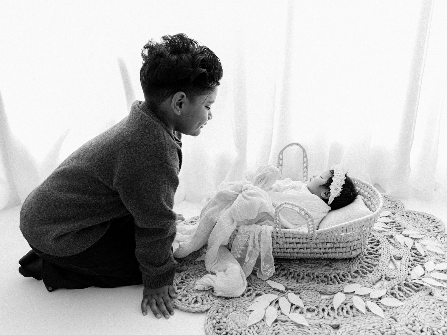 Black and white artistic series showing baby crawling on textured surface.