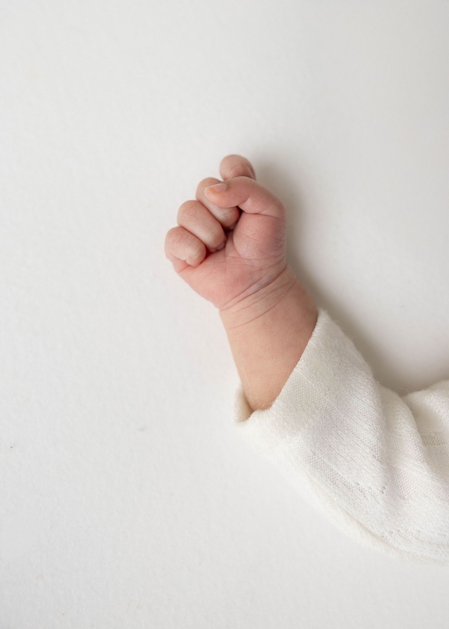 Close-up sequence of tiny baby hand and arm against white background.