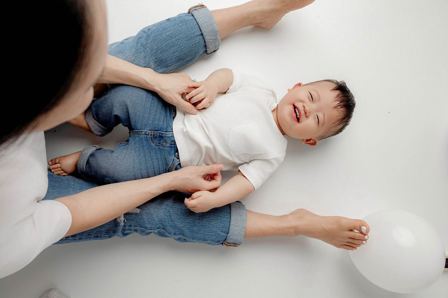 Person lying on white floor in casual clothing in artistic photo sequence.