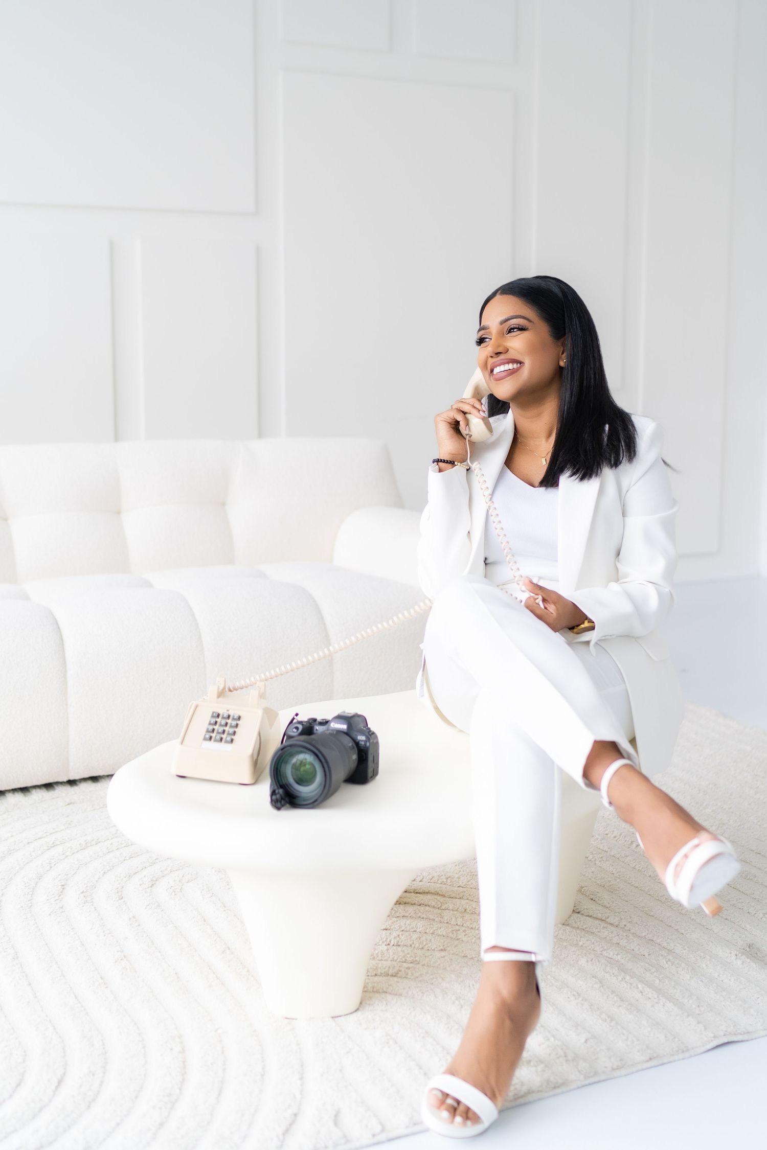 Lifestyle photoshoot in all-white room with cozy furniture and camera equipment.