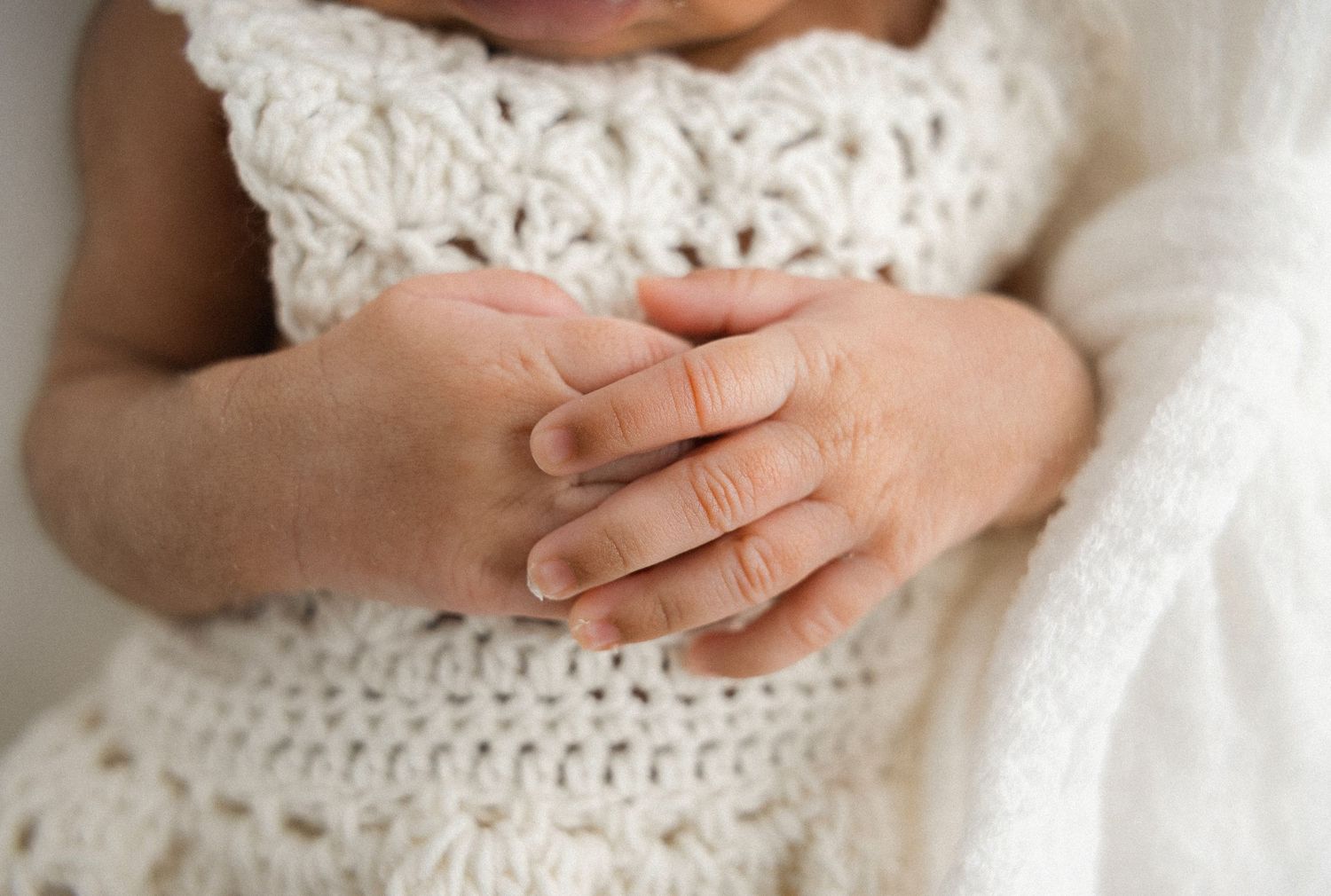 Close-up details of baby's hands and delicate features against white backdrop.