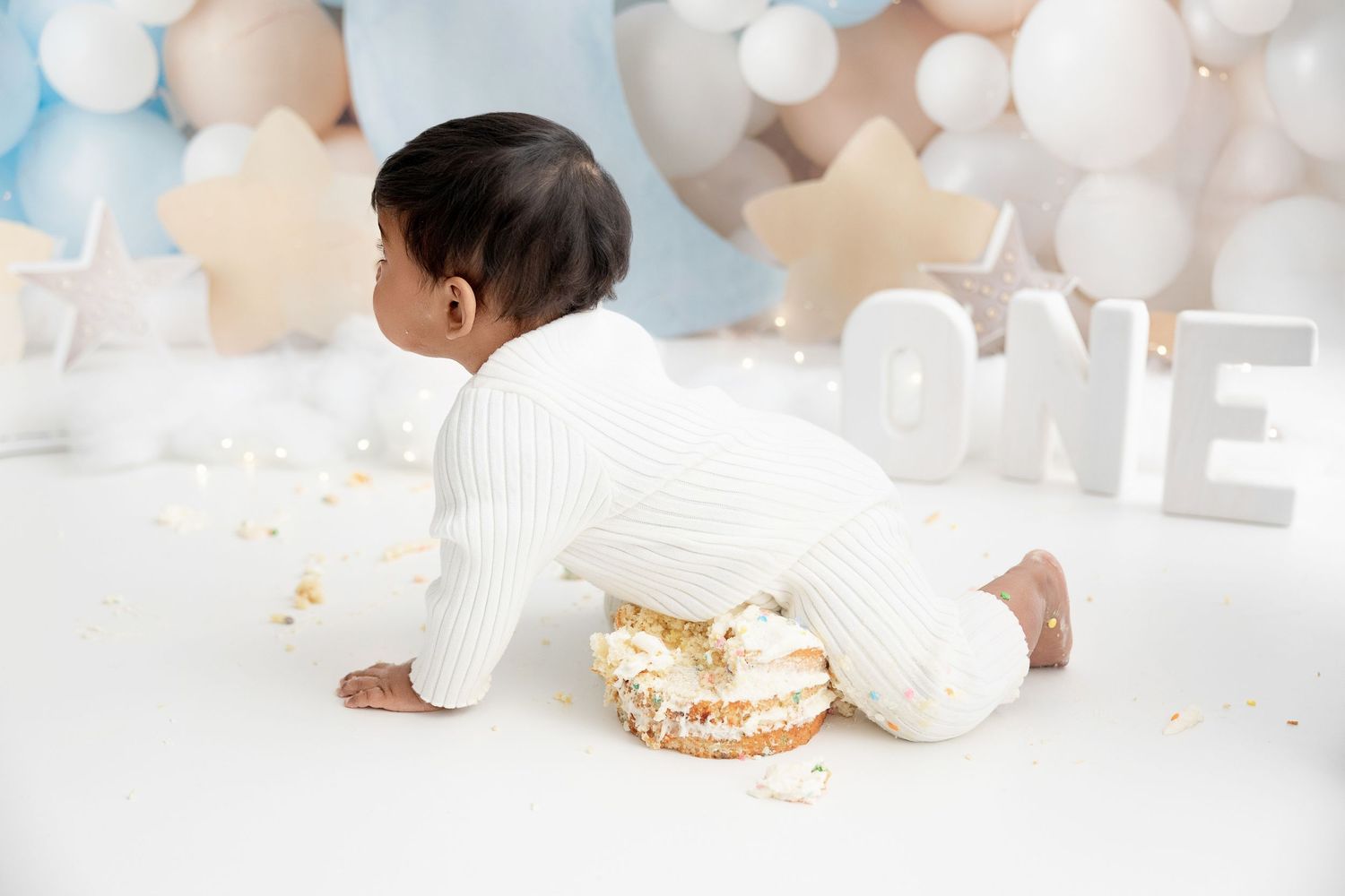 Baby cake smash photoshoot with blue and white balloon decorations.