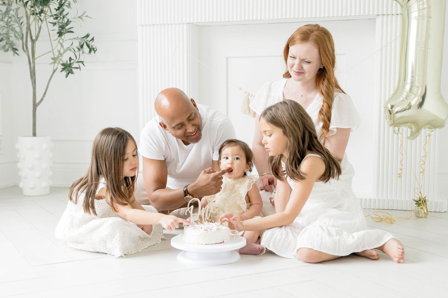 Family photoshoot in an all-white studio setting with minimalist styling.