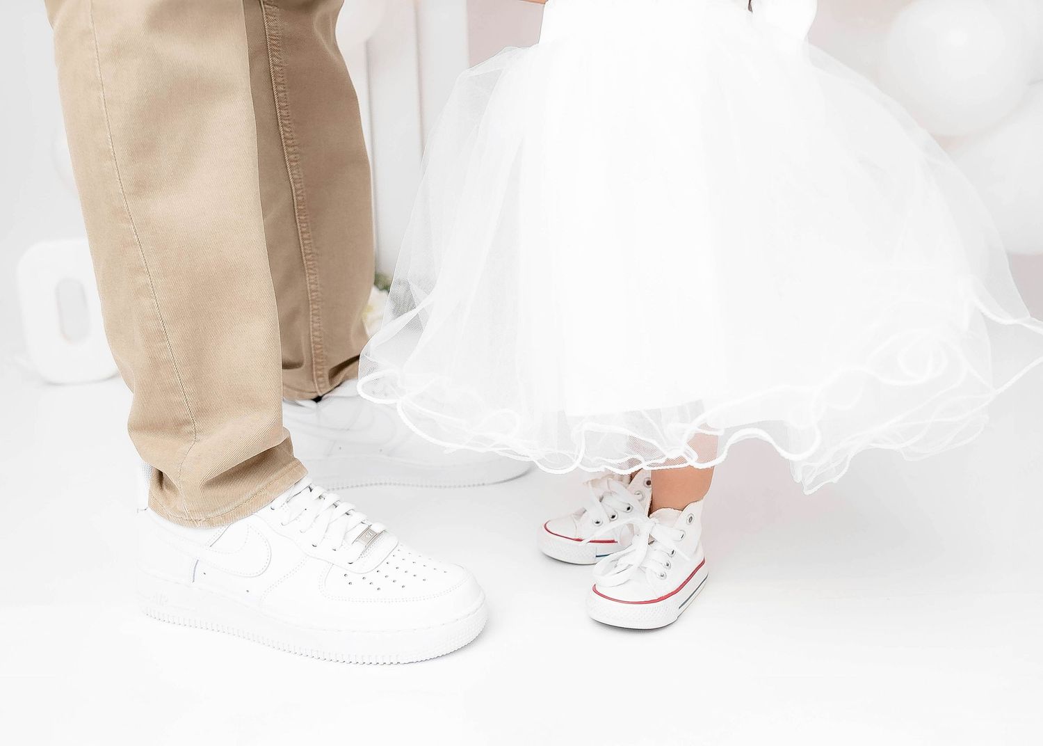 Detailed view of casual footwear and clothing against white studio backdrop.