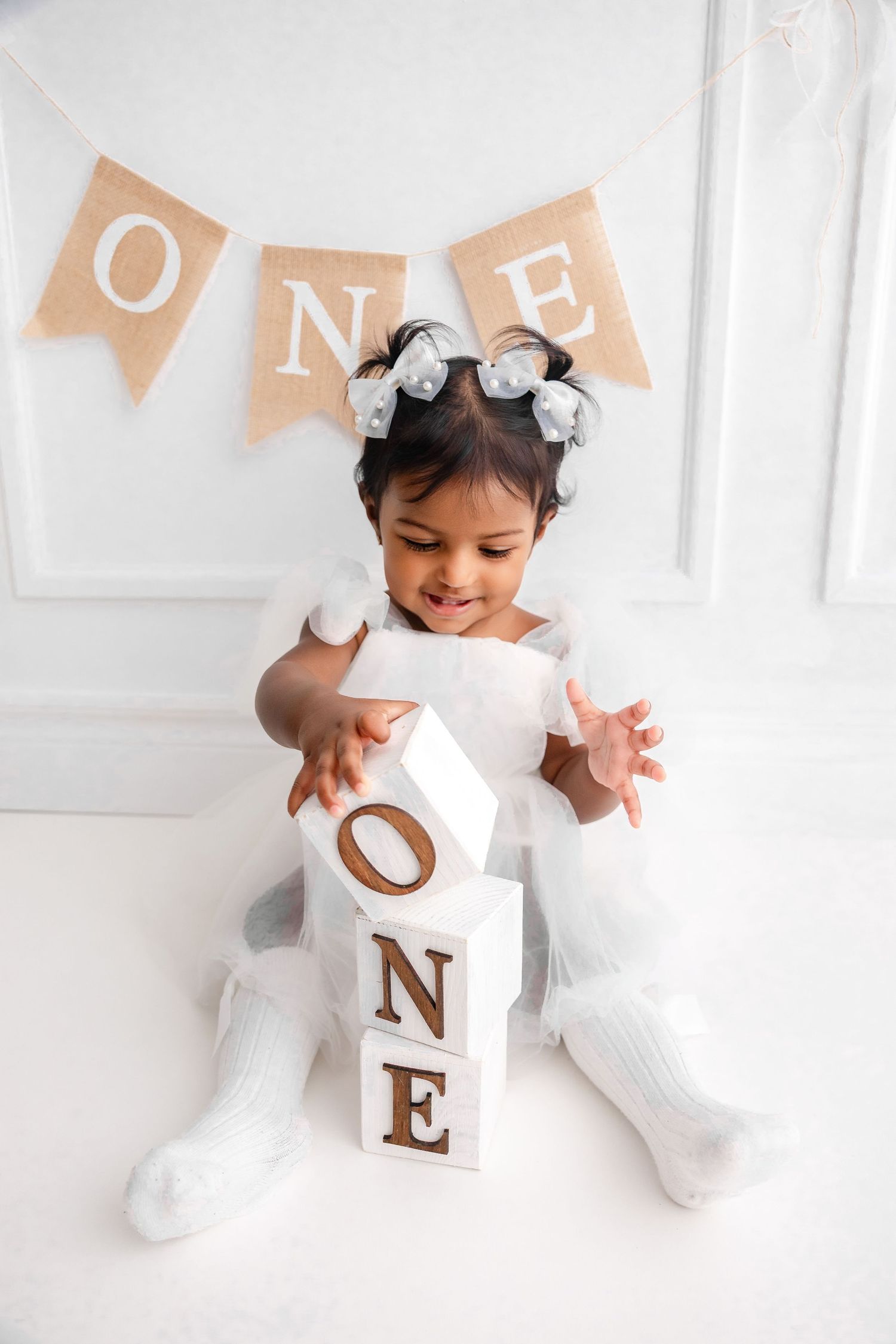 White decorative letter blocks spell ONE against a clean white backdrop with peach banners.