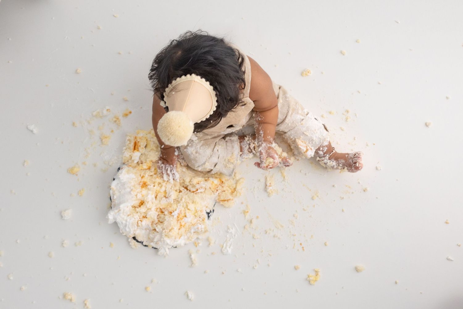 Overhead view of cake crumbs scattered on white surface during cake smash session.