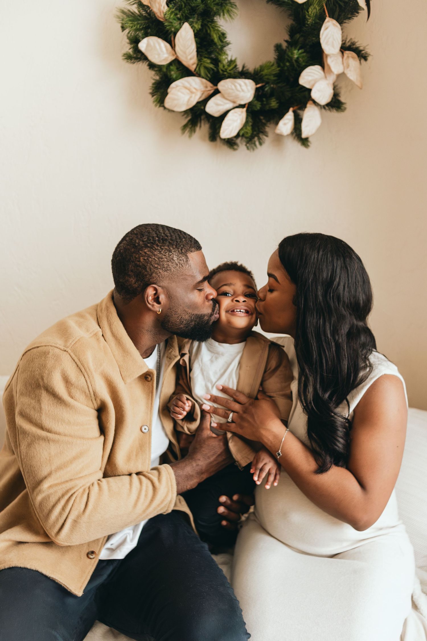 Sweet family moment captured under a decorative wreath during holiday season.