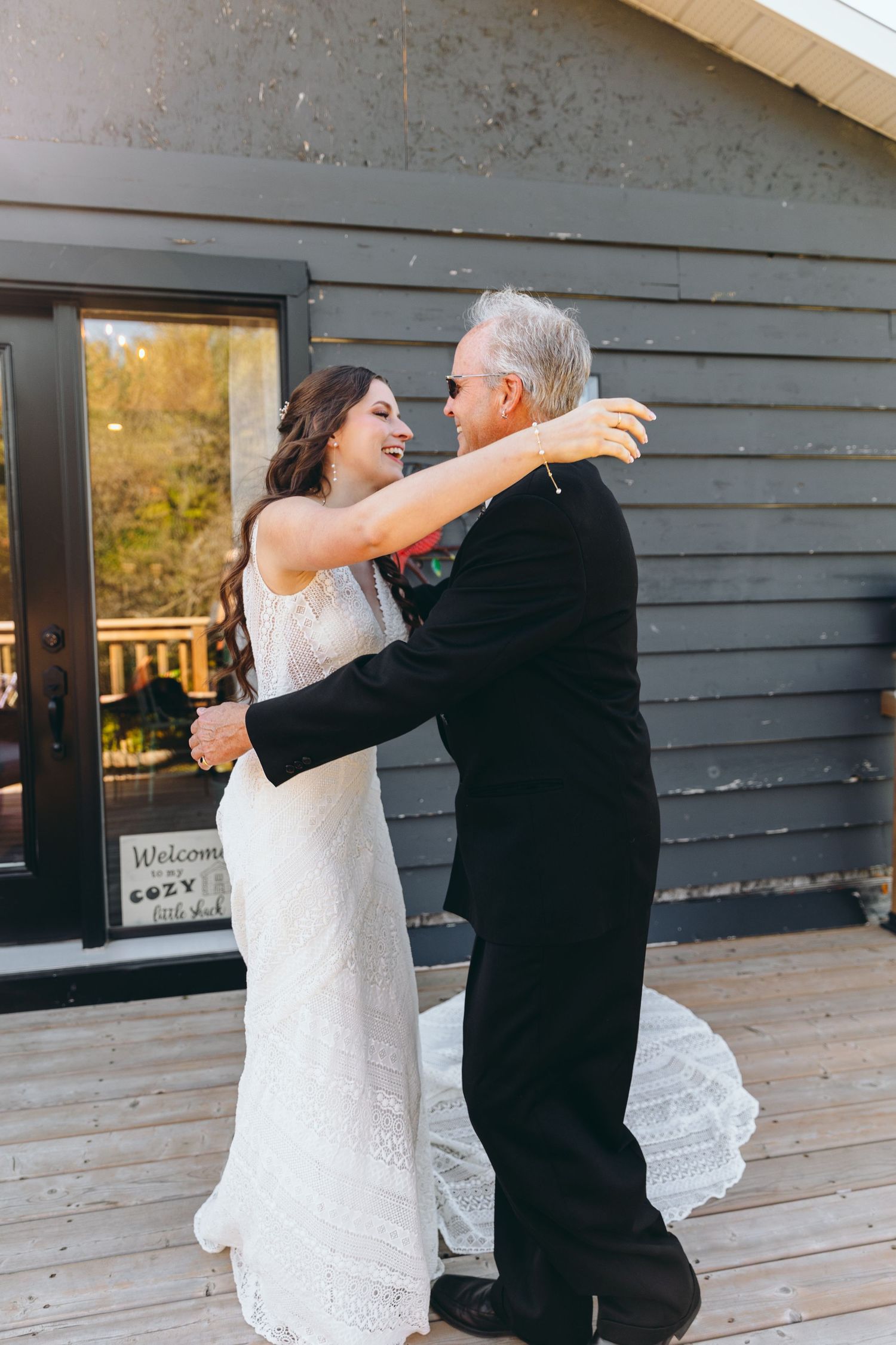 A couple shares a playful dance moment on a wooden deck.