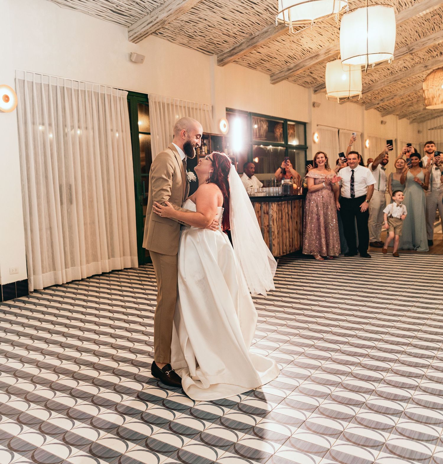 Wedding couple shares intimate dance moves on geometric floor while guests watch from the sides.