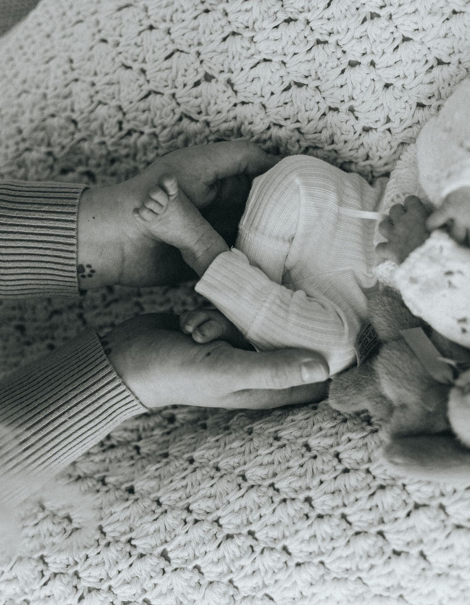 Black and white close-up of sleeping newborn on textured surface.