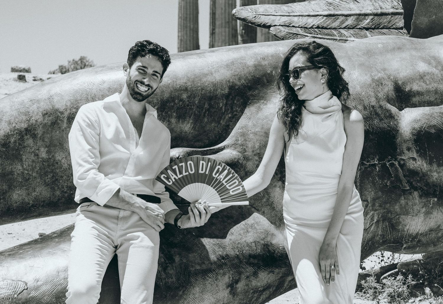 Playful dance poses captured in black and white photography near Greek architecture.