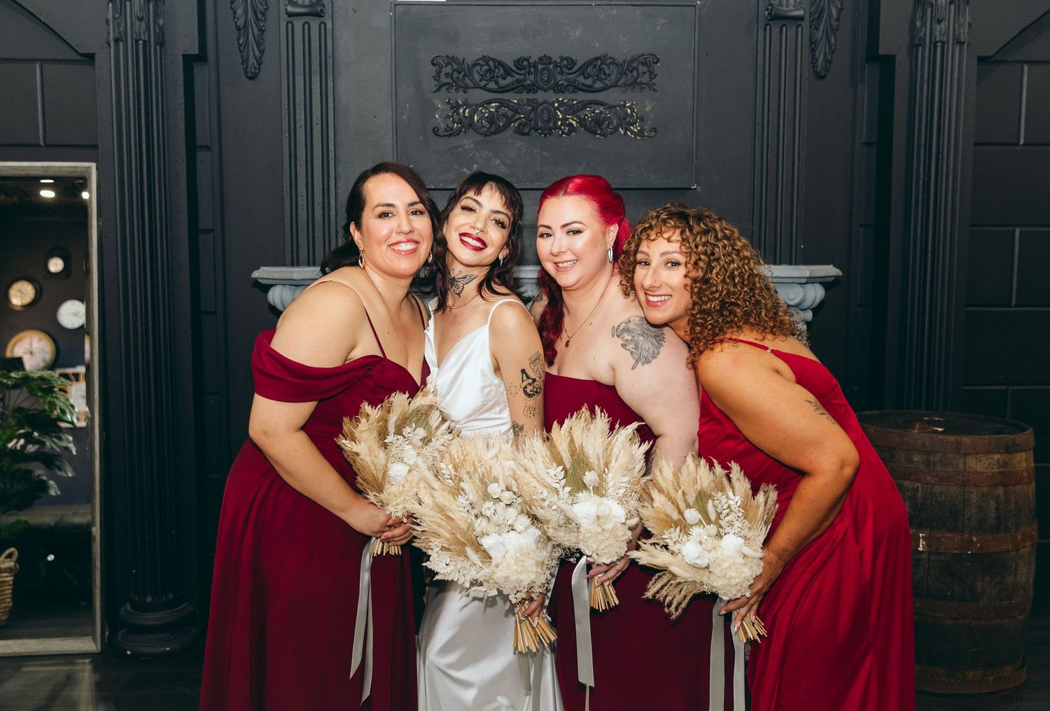 Wedding party poses with dried palm leaf bouquets in formal attire.