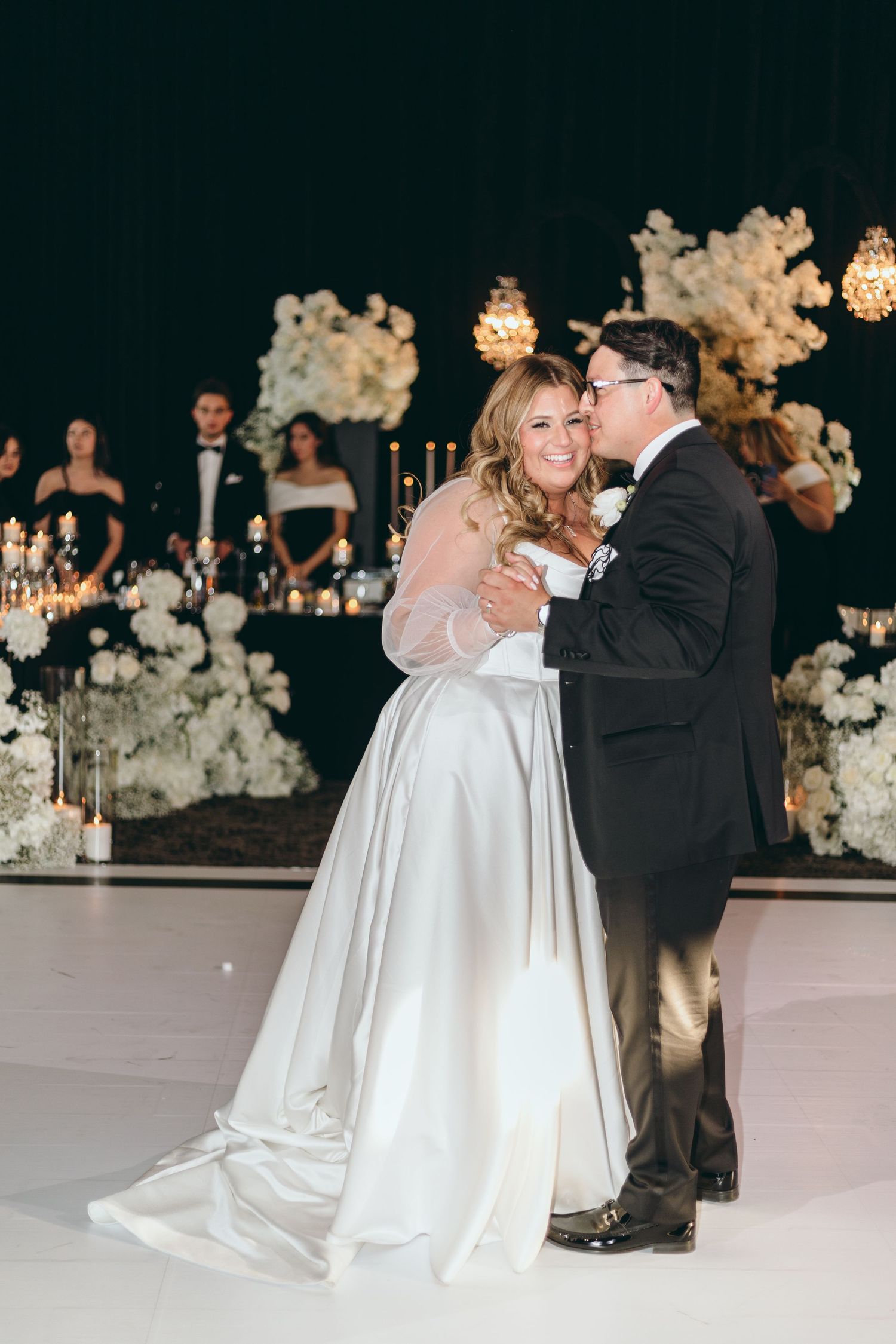 Wedding couple sharing an intimate dance moment surrounded by white floral arrangements.