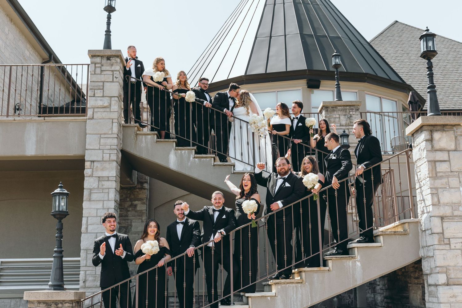 Wedding group arranged on elegant curved staircase for formal portrait.