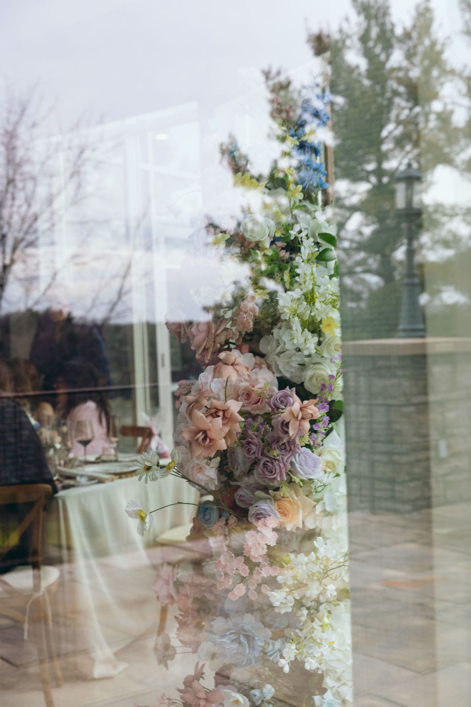 Soft focus floral arrangements with pink and white blooms reflecting in window glass.