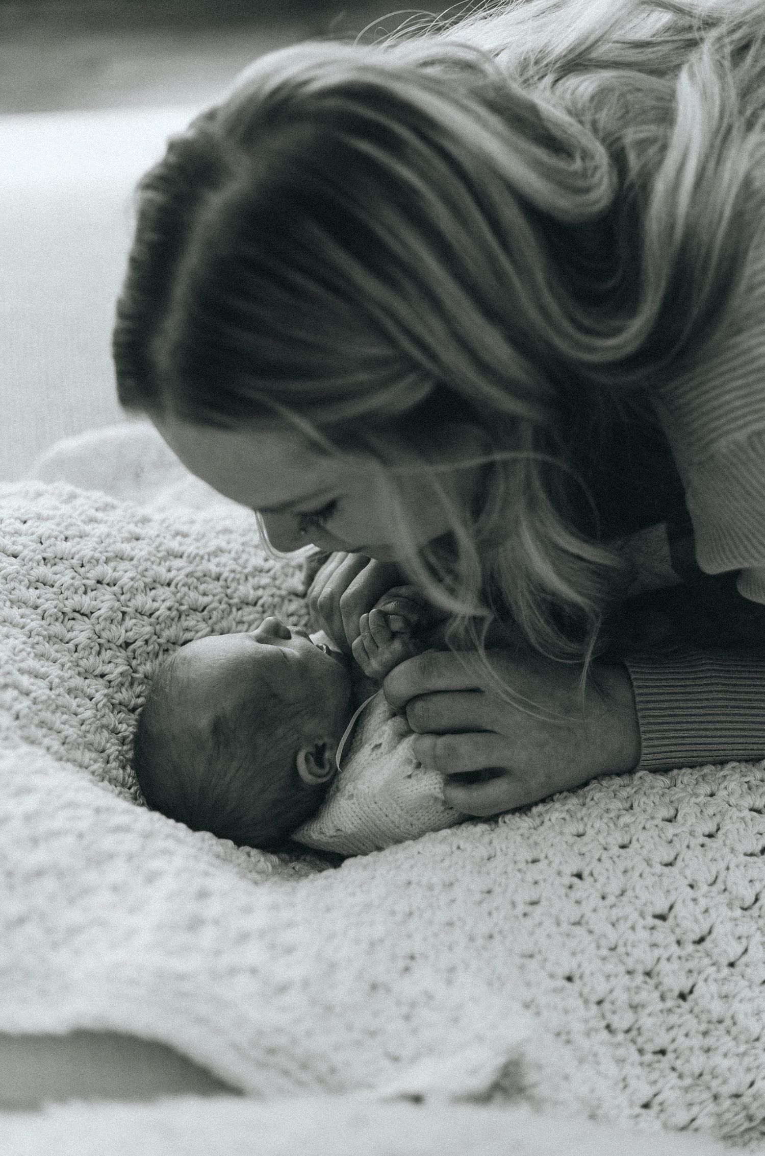 Black and white series showing tender moments with a baby on a crocheted blanket.