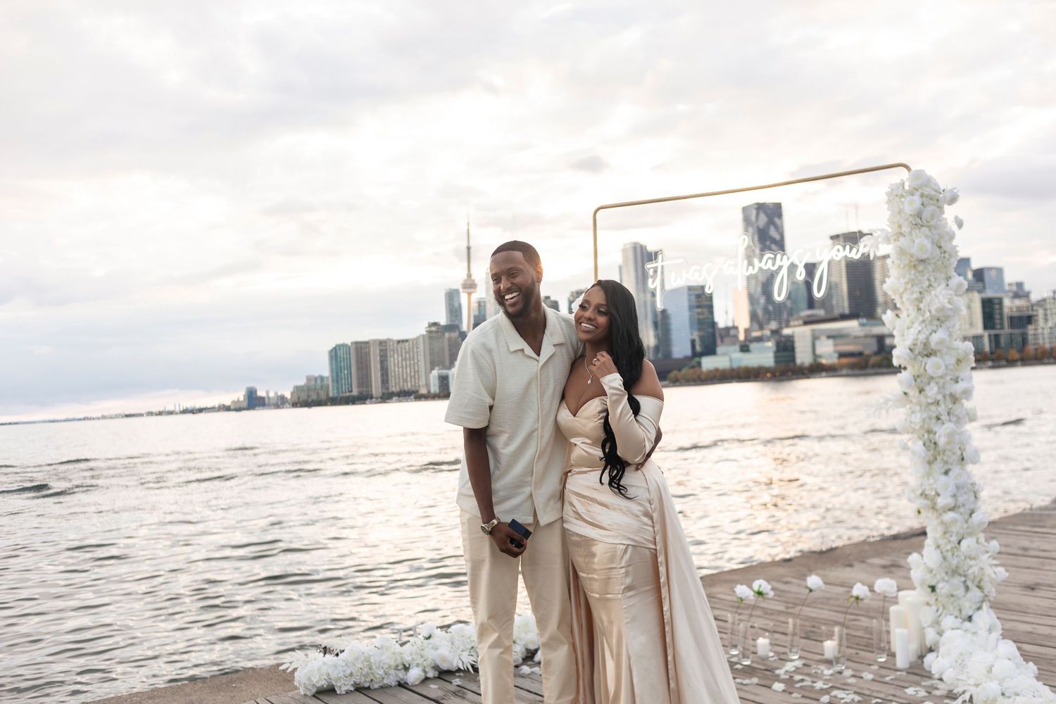 A romantic waterfront scene with decorative white floral arrangements at sunset.