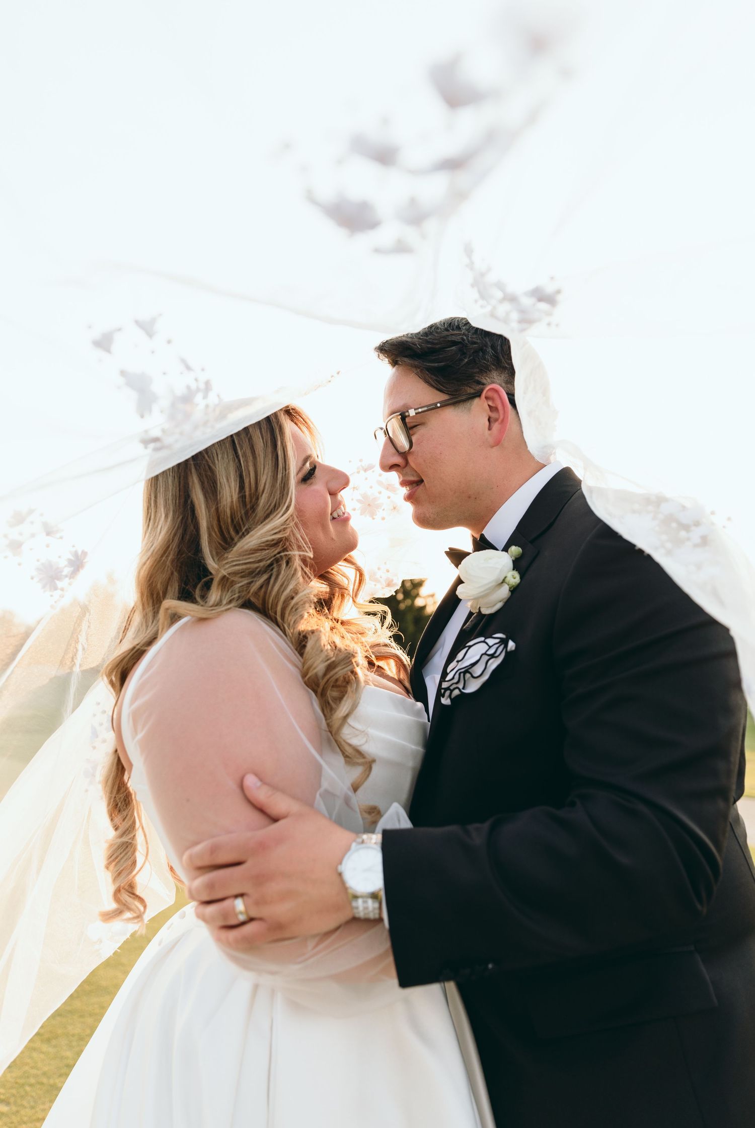 A tender moment between newlyweds under a bright sky on their wedding day.