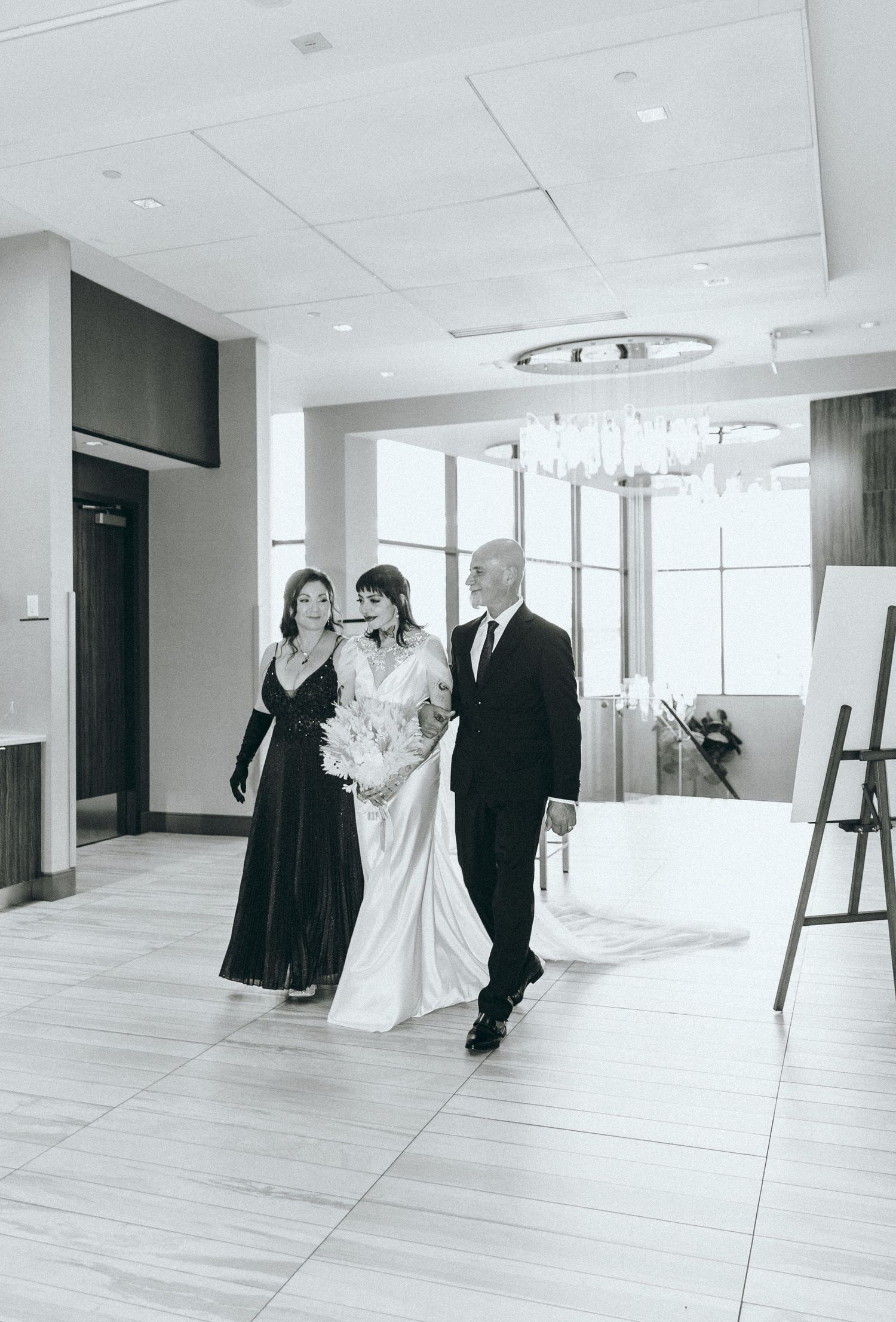 Black and white wedding ceremony photos showing couples in a modern venue with white walls and floors.