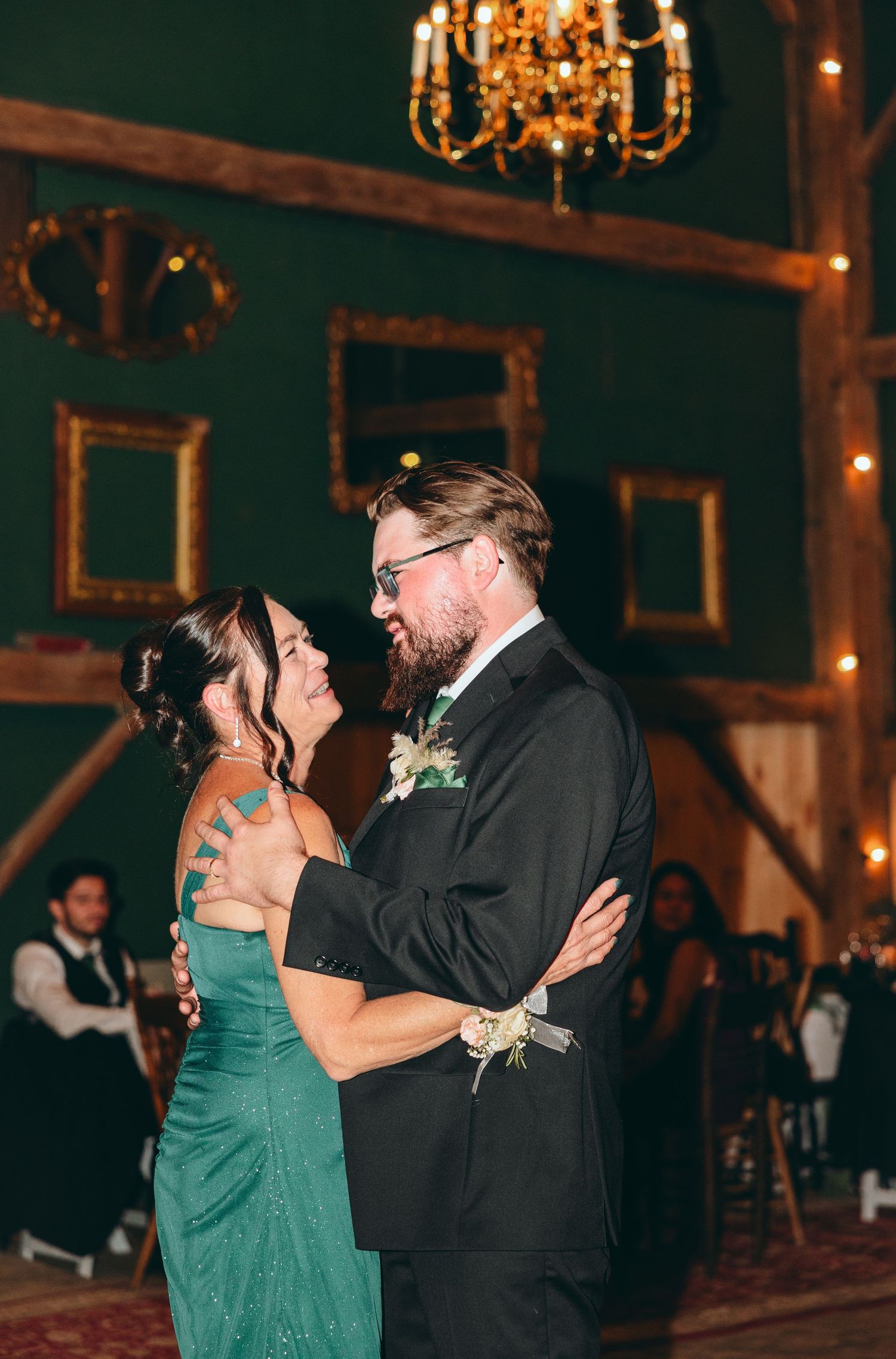 Dancing couple in formal wear share an intimate moment on rustic wooden dance floor.