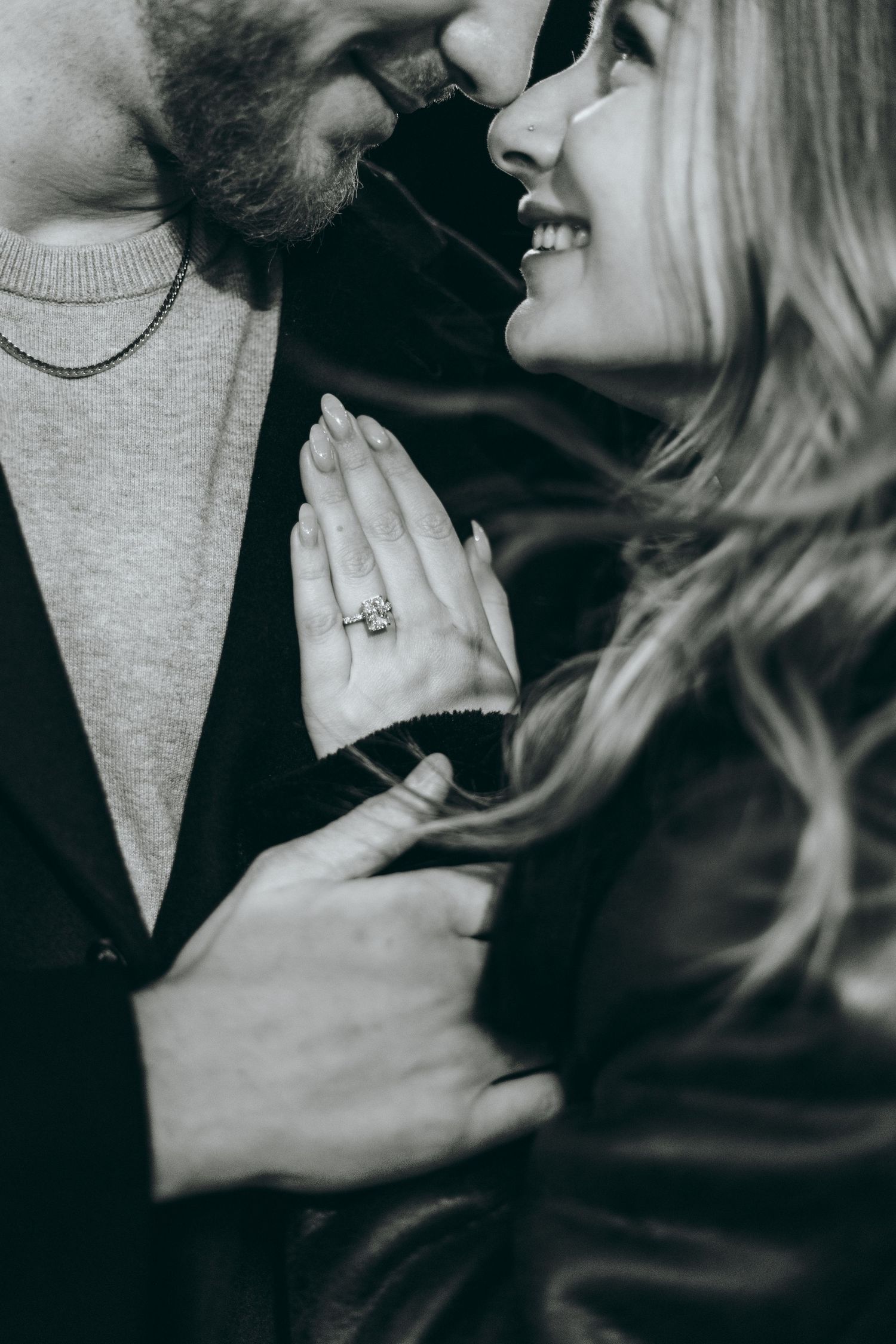 Emotional close-up of couple sharing tender moment with engagement ring visible.