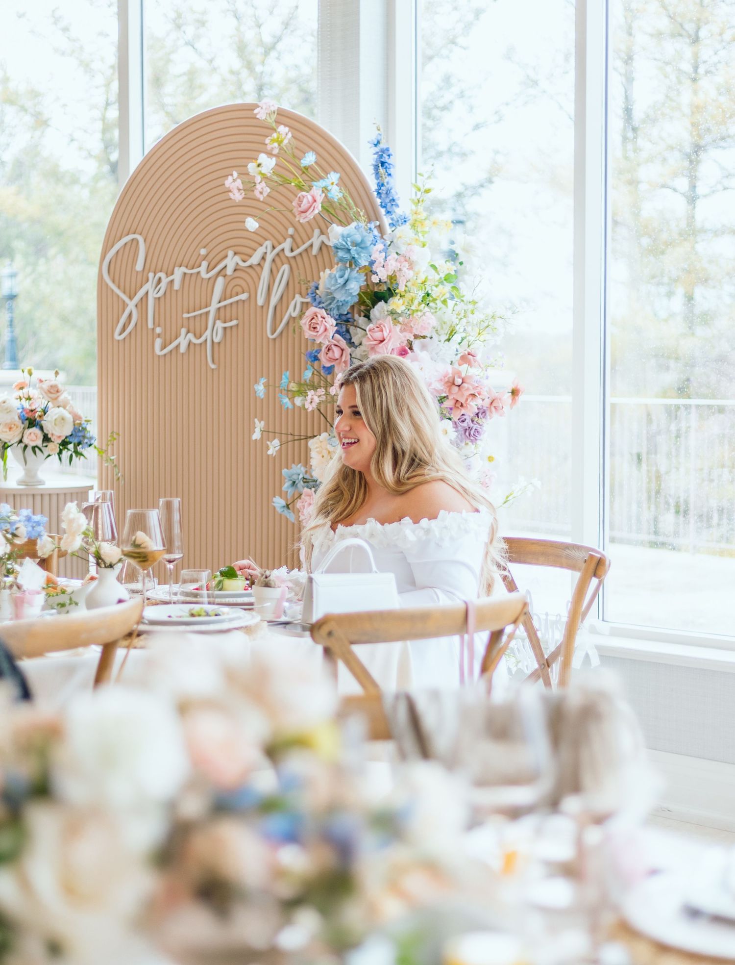 Light-filled reception room with elegant place settings and floral arrangements in soft pastel colors.