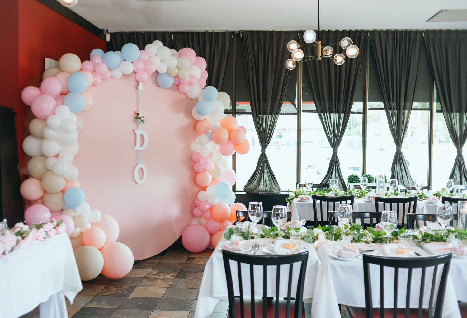 Event space decorated with pink and white balloon arch and elegant table settings.