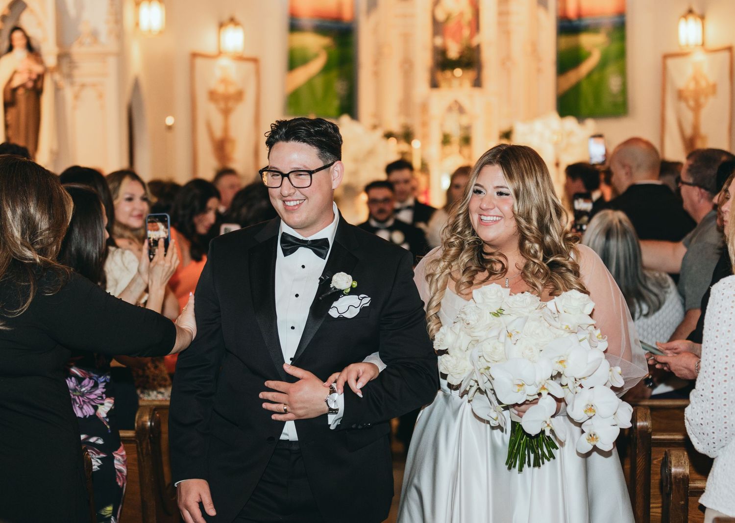 Wedding reception in an elegant ballroom with chandeliers and ornate decor.
