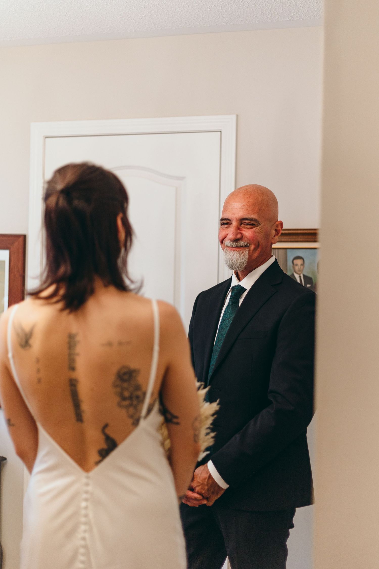 Emotional first look between person in white wedding dress and suited figure in indoor setting.