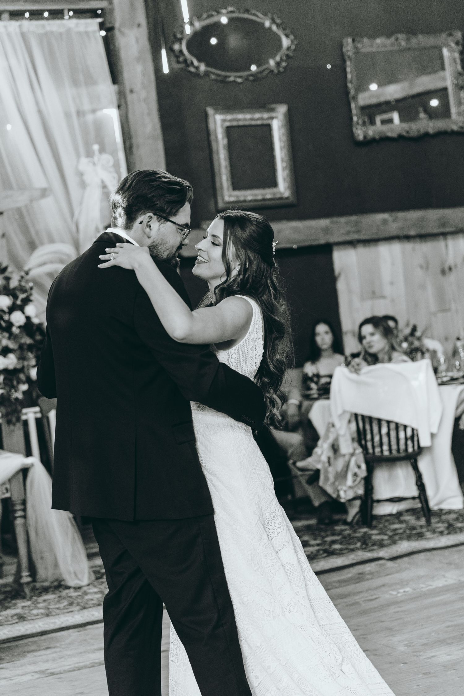 Black and white photo of couple's romantic first dance in rustic venue setting.