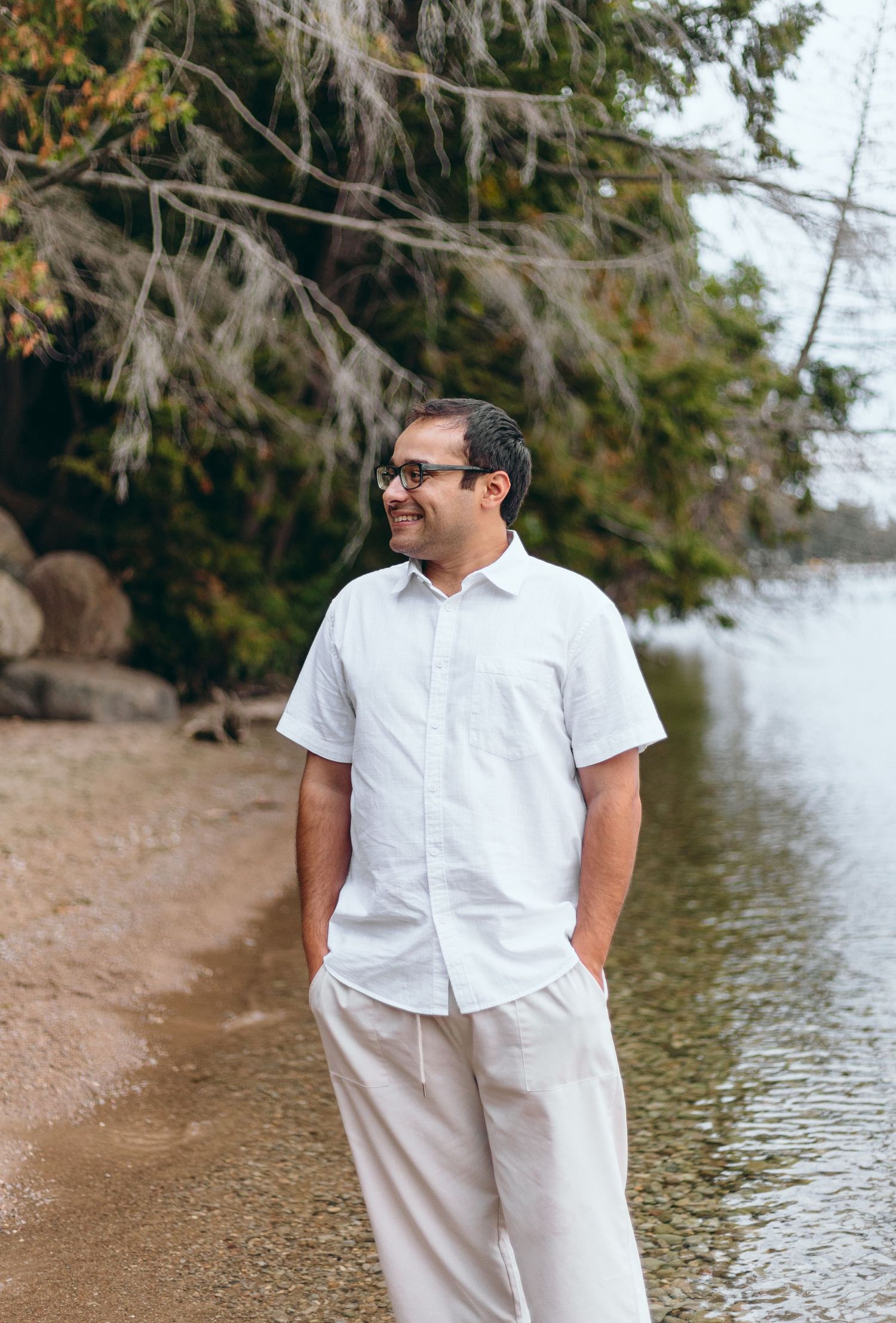 Person in white shirt and khaki pants smiling on beach shoreline.
