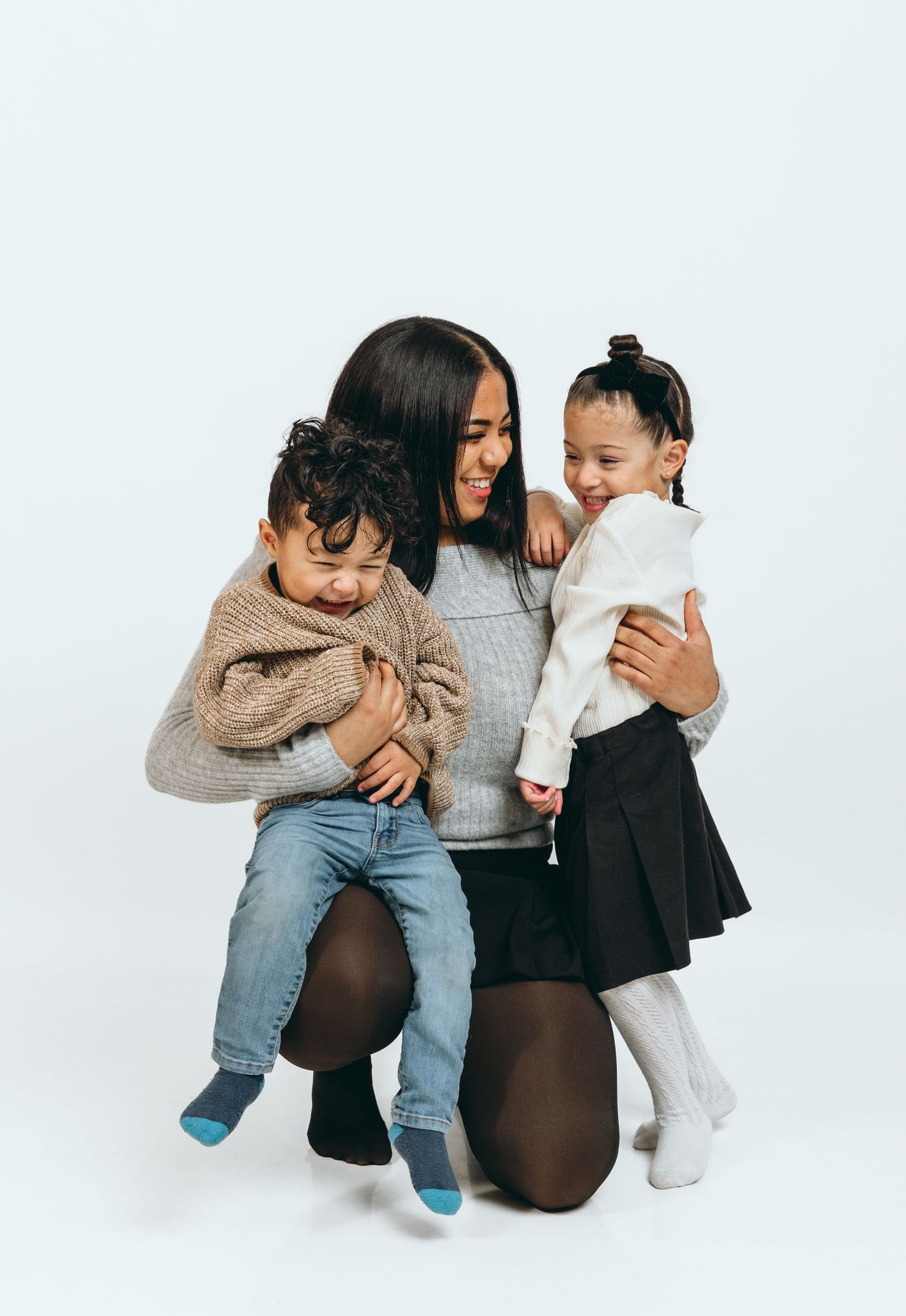 Loving family moment captured against white background in coordinated casual outfits.