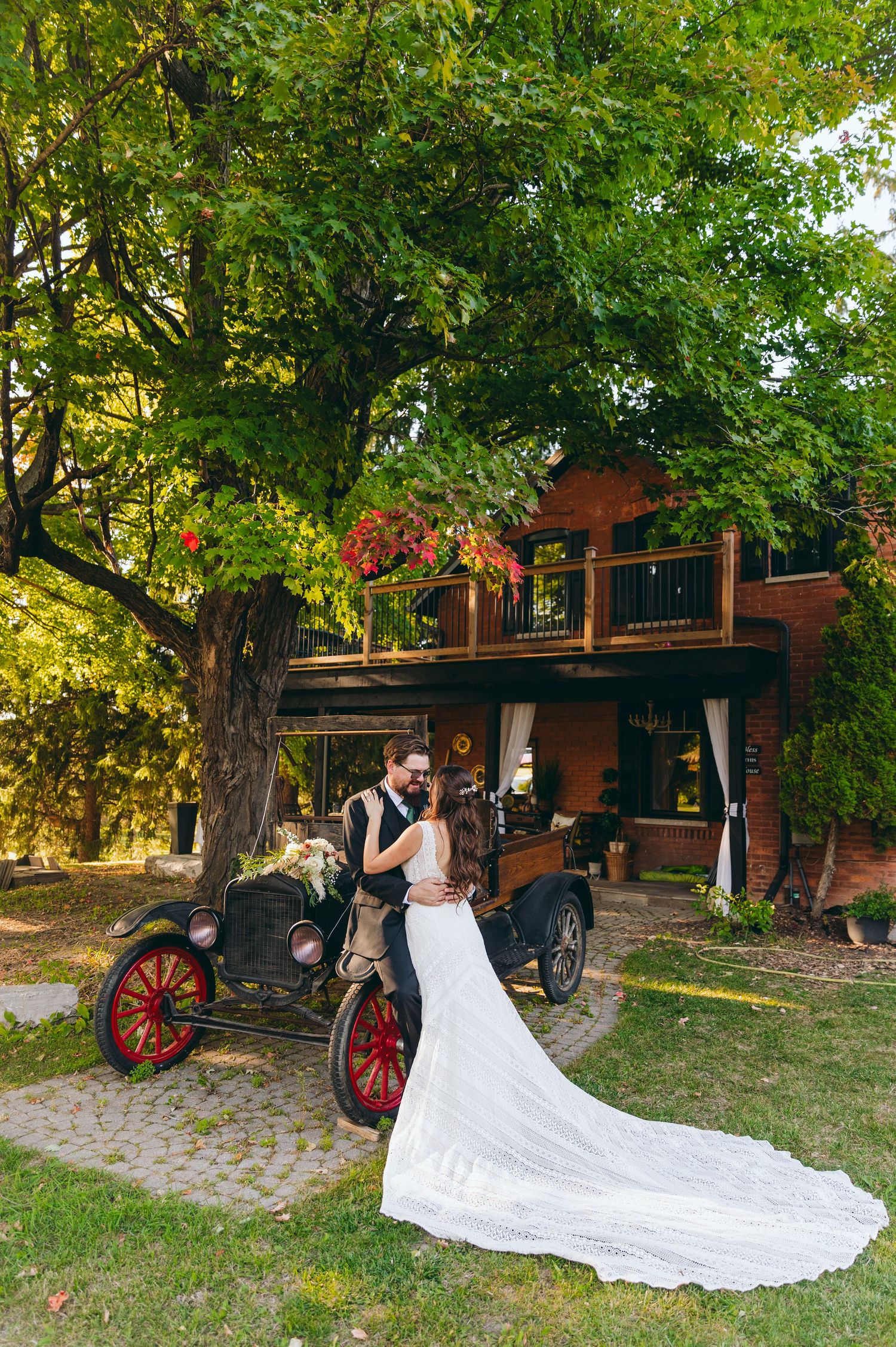 A flowing white wedding dress train elegantly draped beside an antique horse-drawn carriage in a garden setting.