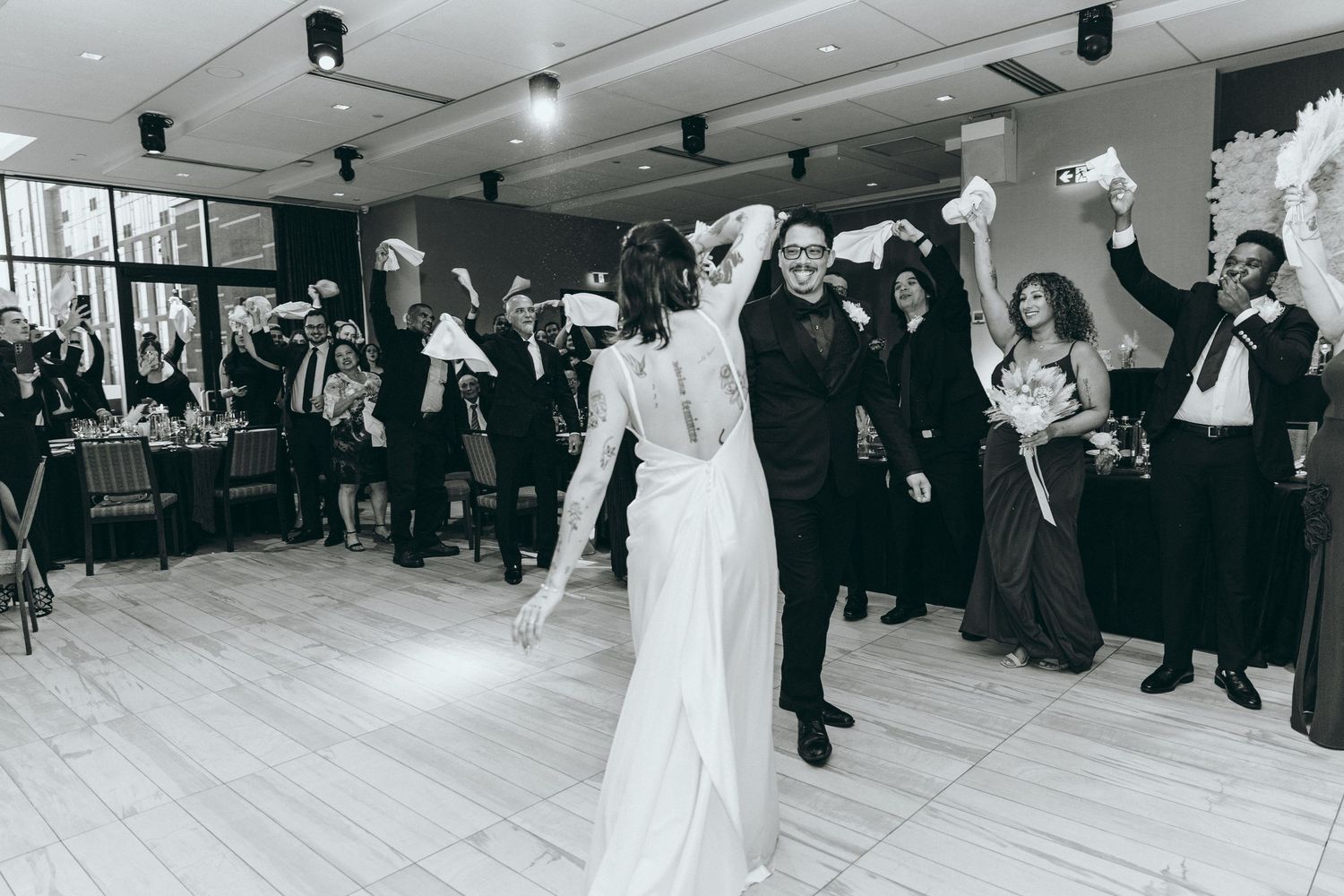 Couples slow dancing on a spacious wooden dance floor during a wedding reception.