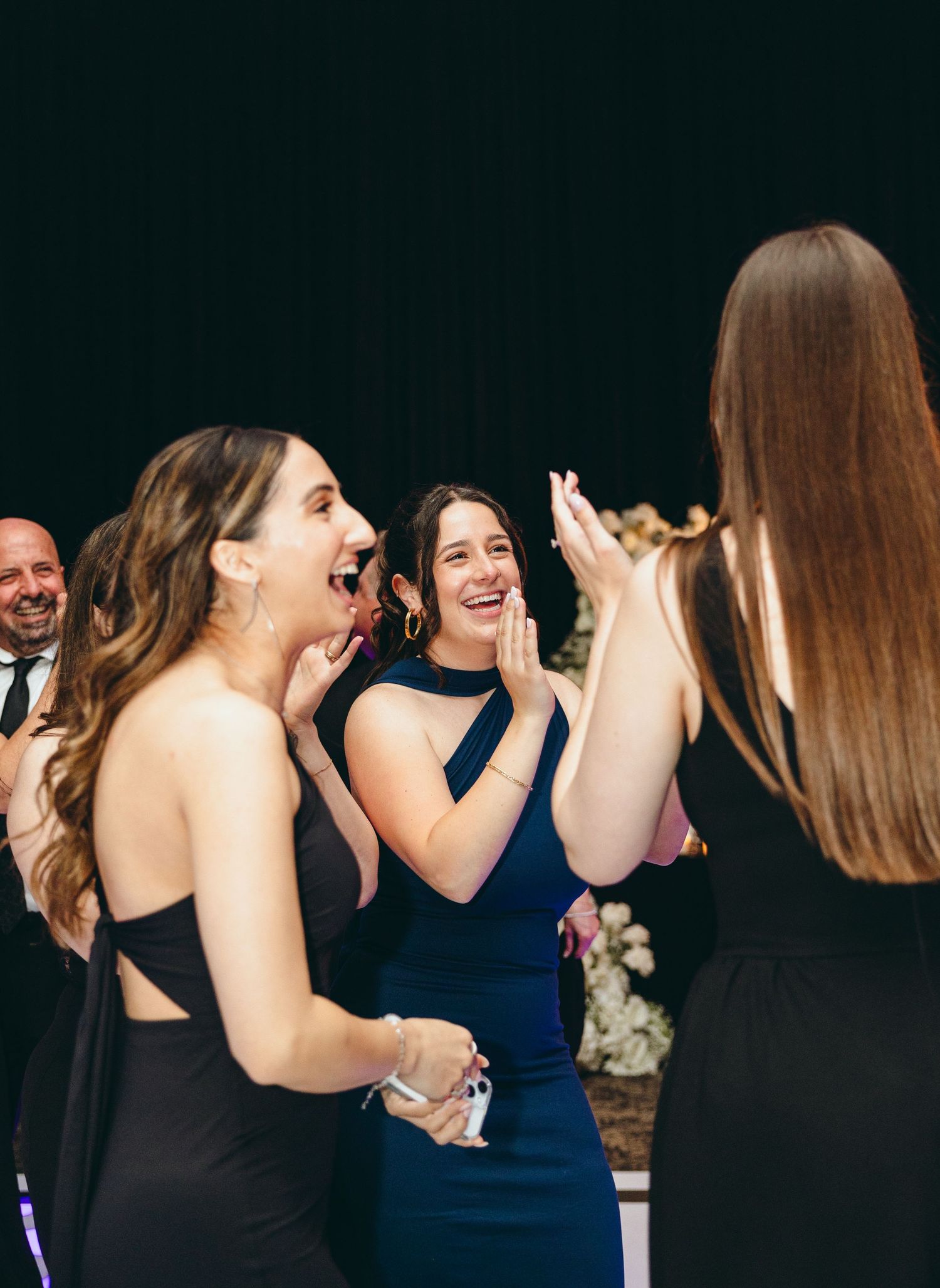 Wedding guests sharing excited reactions and laughter during reception celebration.