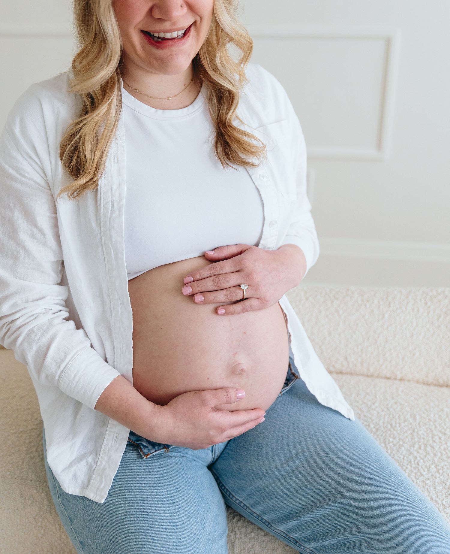 Casual maternity photos showing pregnant belly with white top and blue jeans.