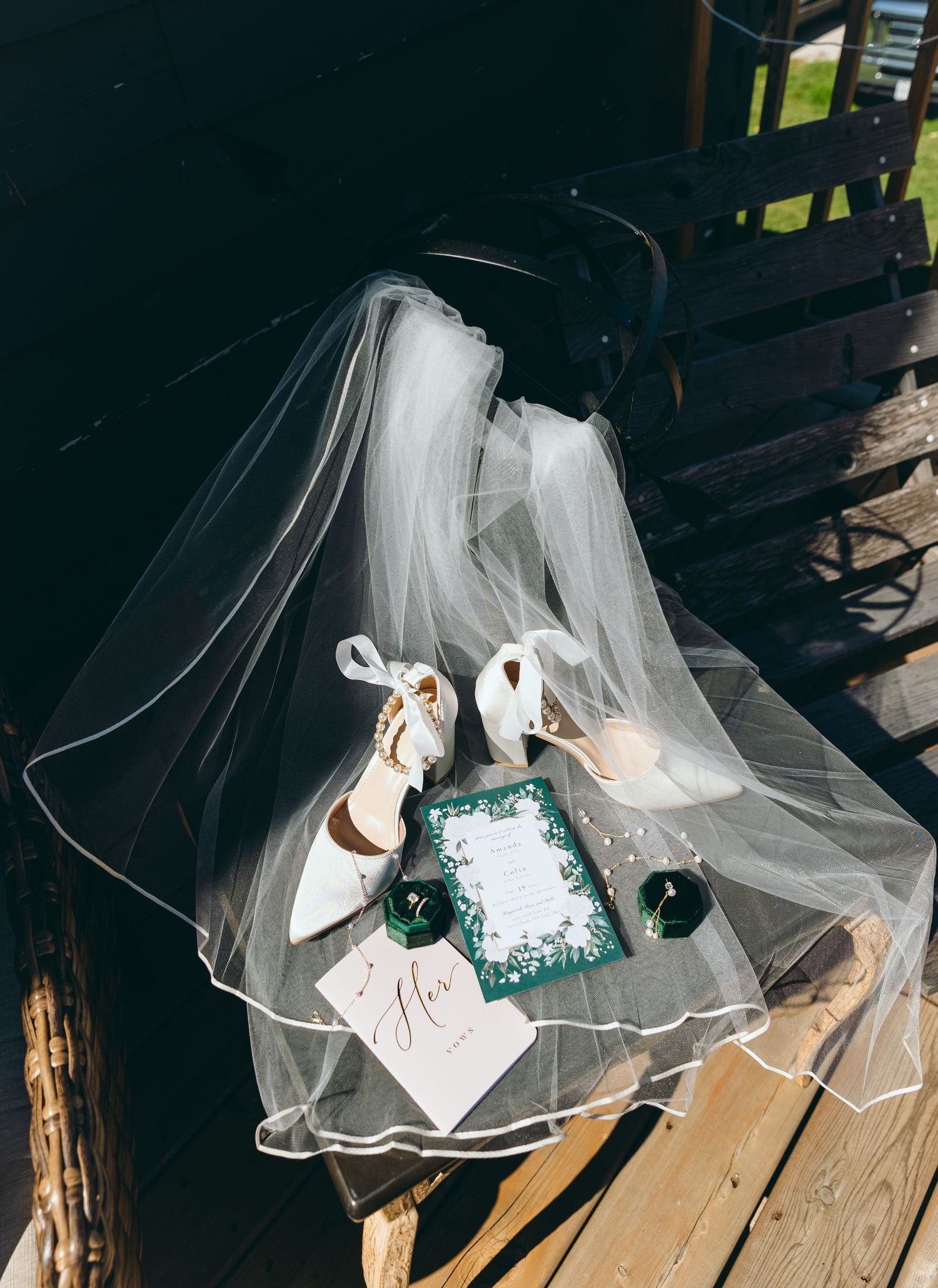 Wedding details flat lay with veil, white shoes and emerald green accents.