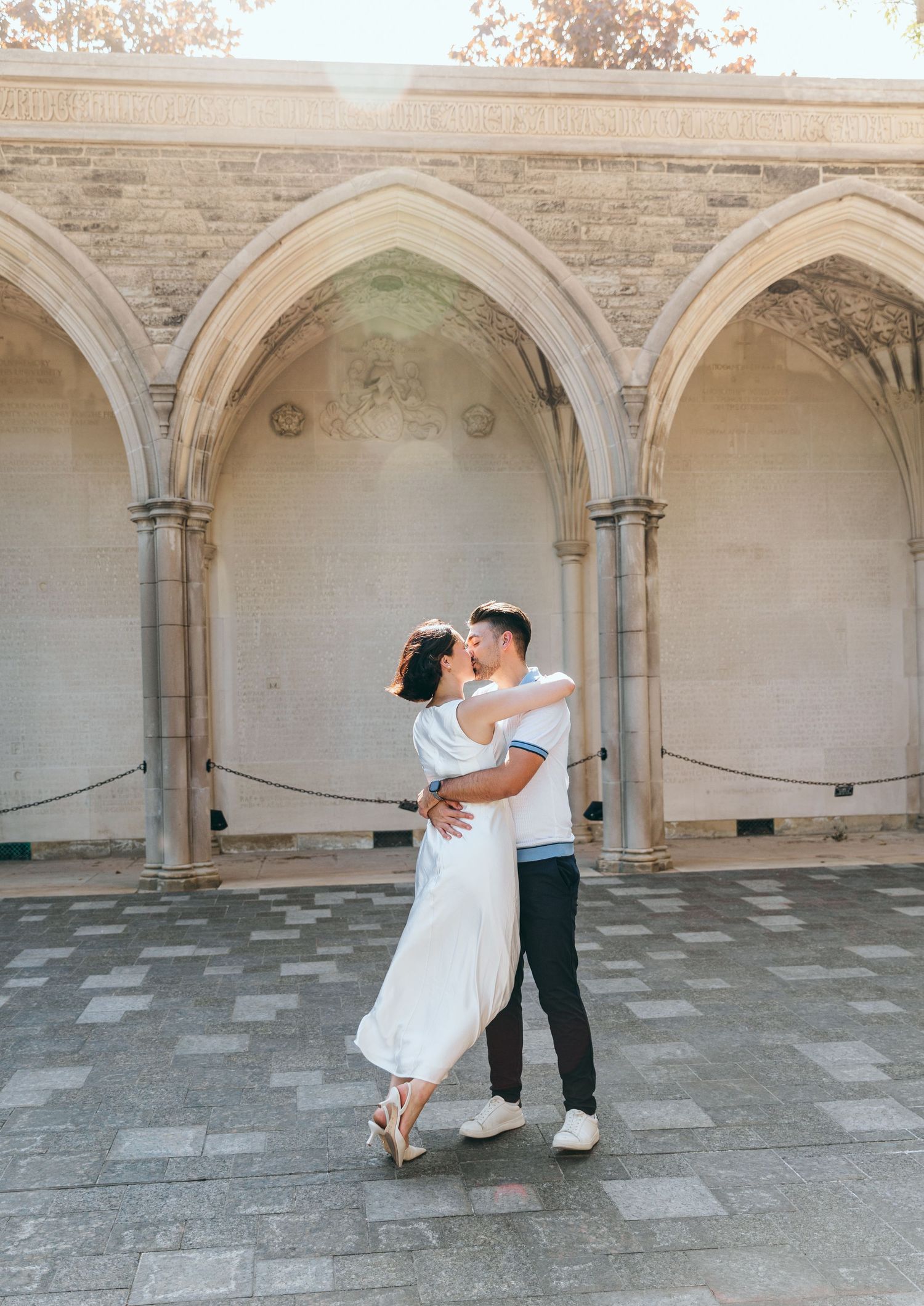 A couple embraces and dances in an elegant stone corridor with gothic arches.