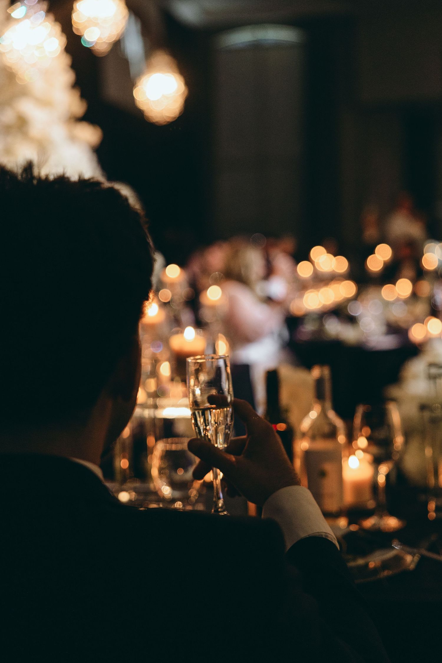 Candlelit reception tables create romantic ambiance at evening wedding celebration.