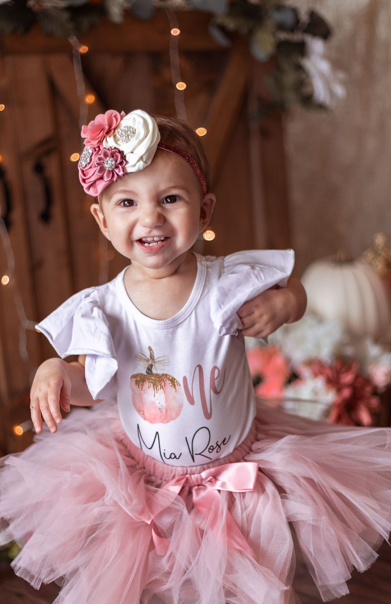 Pink tutu birthday photo session with rustic barn door background and floral accents.
