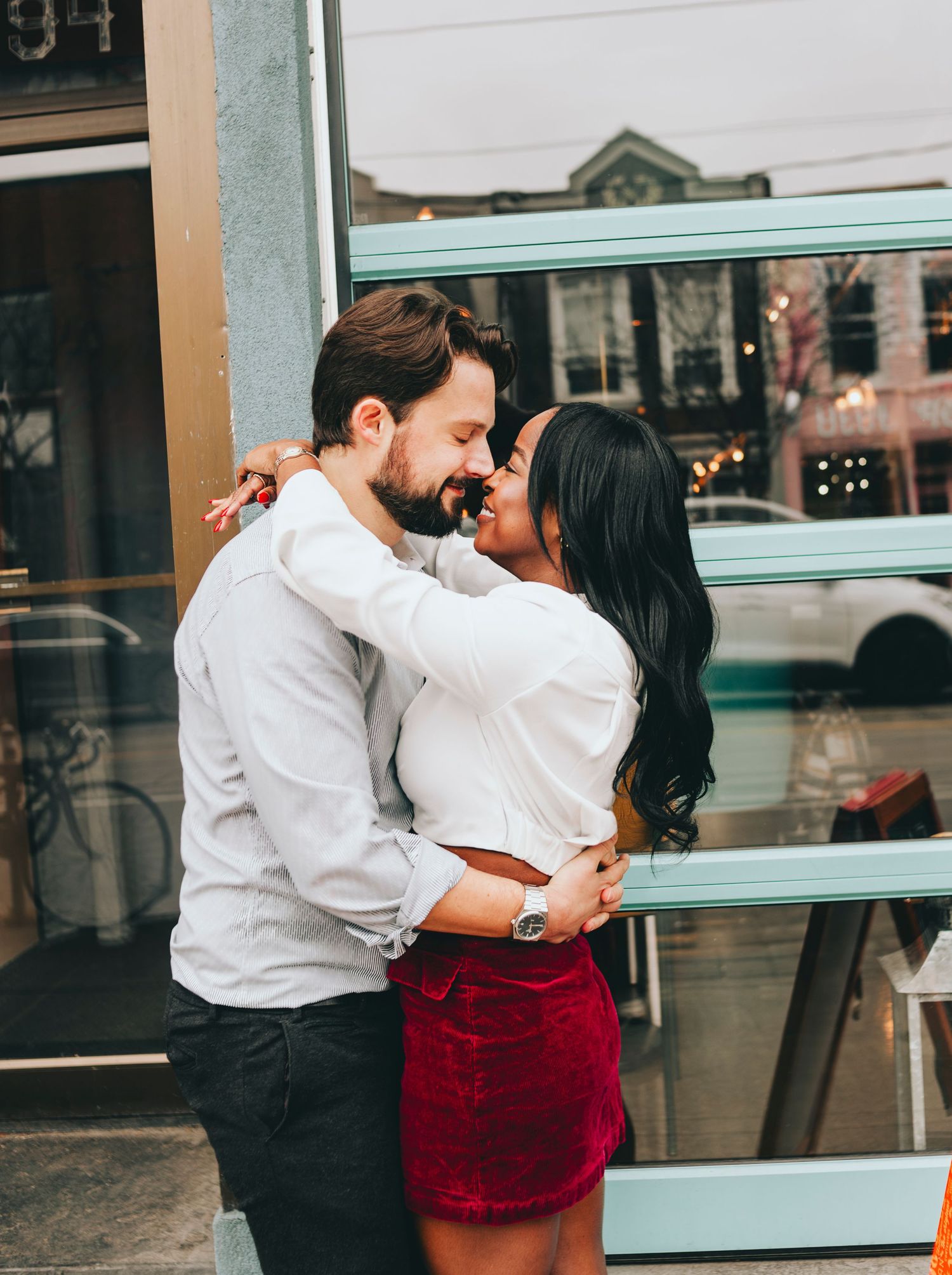 Romantic couple embracing near a storefront window.