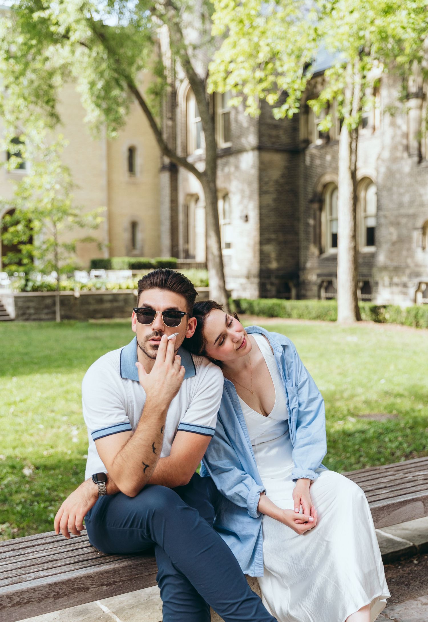 Couple sharing playful moments on a bench in a sunny garden setting.